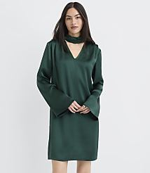 A woman wearing a long-sleeved, dark green satin dress stands against a plain white background. carousel Product Image 2