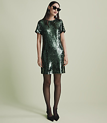A woman wearing a green sequined dress, black tights, and sunglasses stands against a plain light green background. carousel Product Image 4