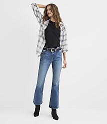 A woman wearing a black t-shirt, an open plaid shirt, blue jeans, and black boots stands against a plain white background. carousel Product Image 1