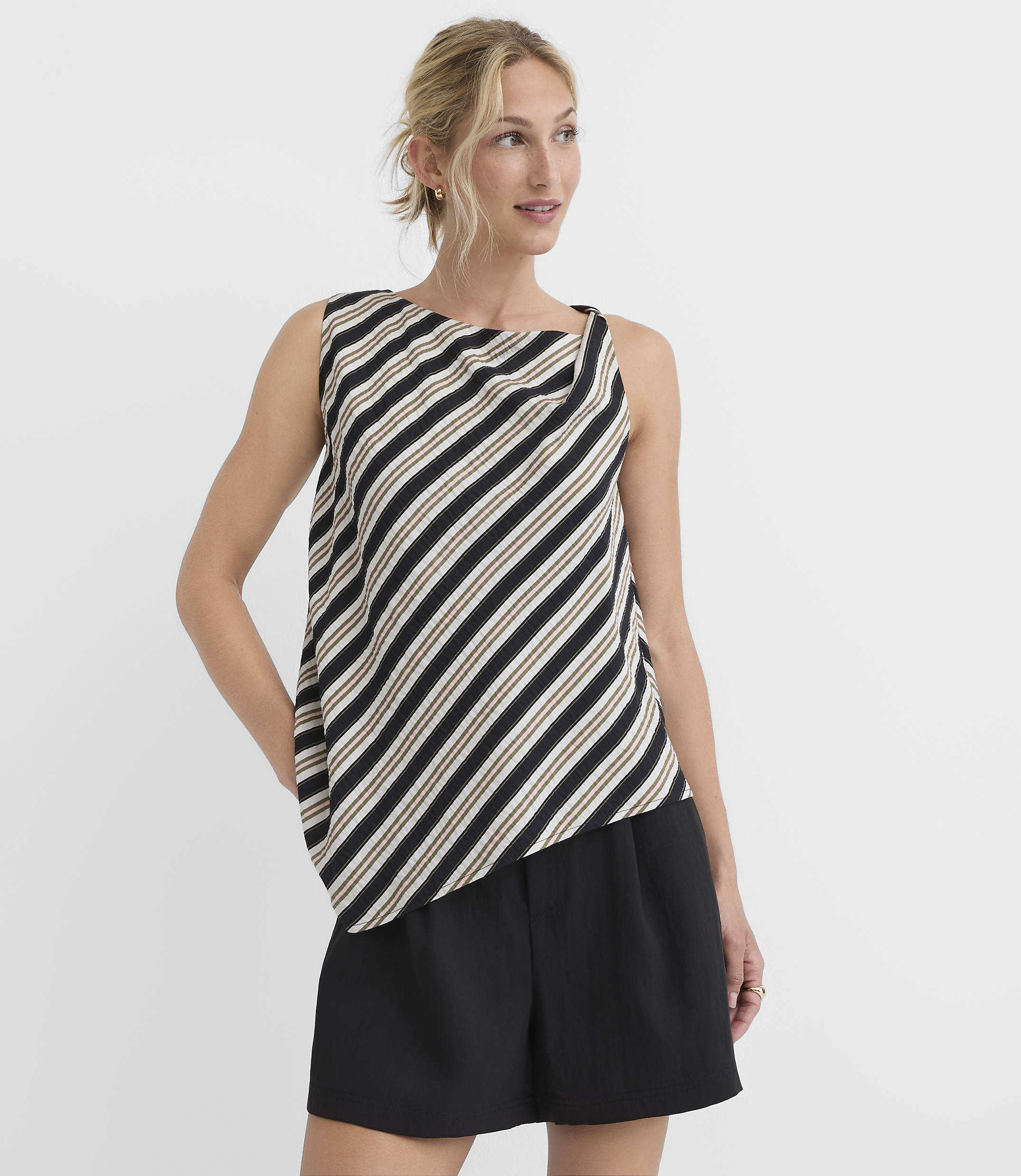 A woman in a striped top and black shorts stands against a plain white background.