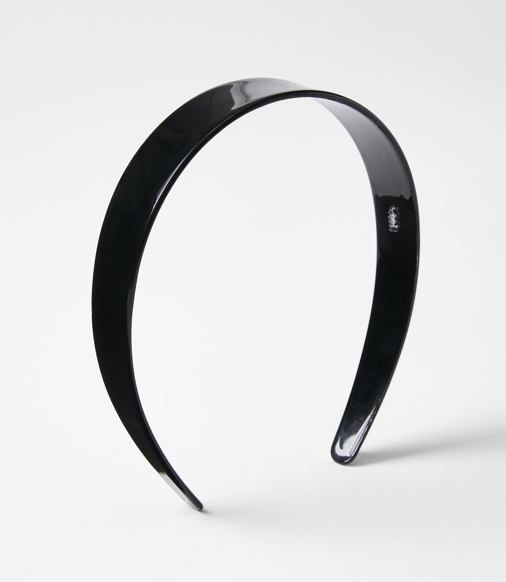 A glossy black headband rests on a plain white background.