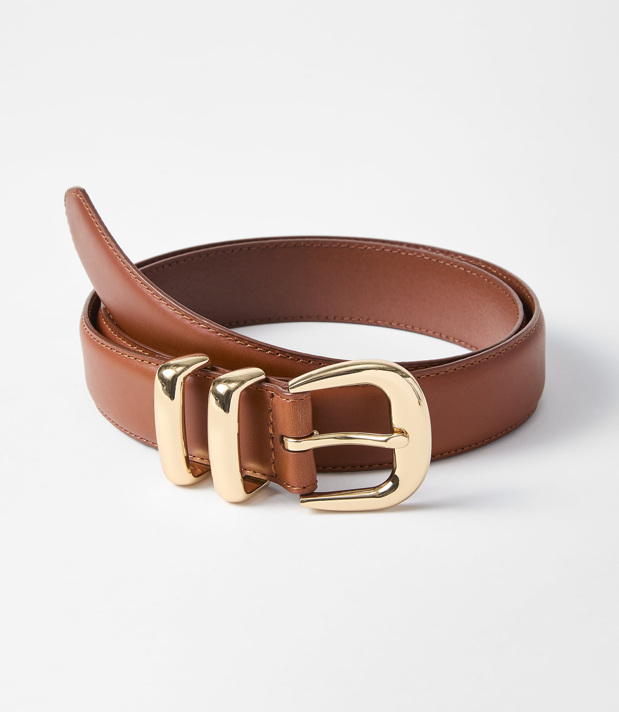 A brown leather belt with a gold buckle is laid out on a white background.
