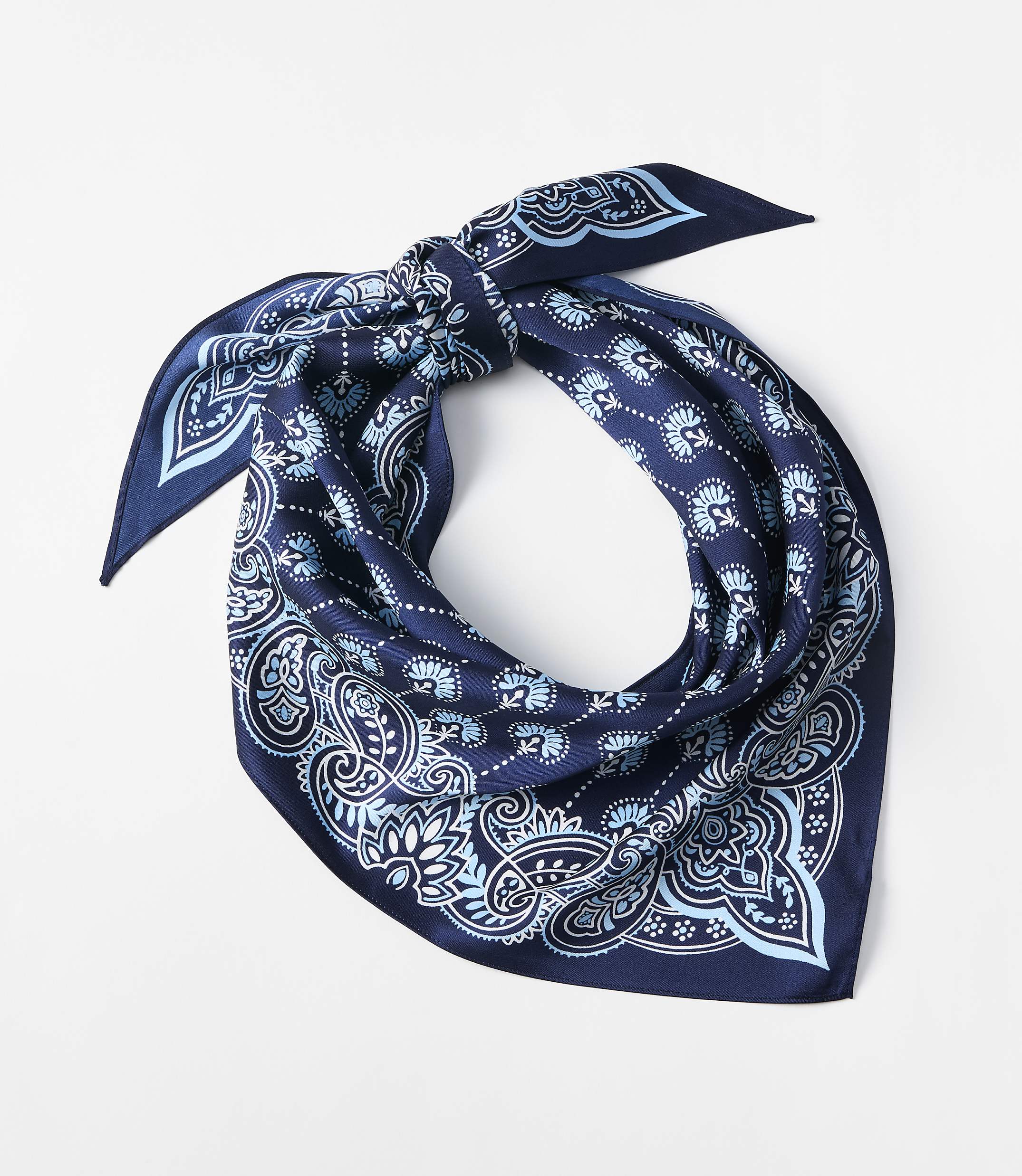 A dark blue bandana with a light blue paisley pattern is tied in a knot against a plain white background.
