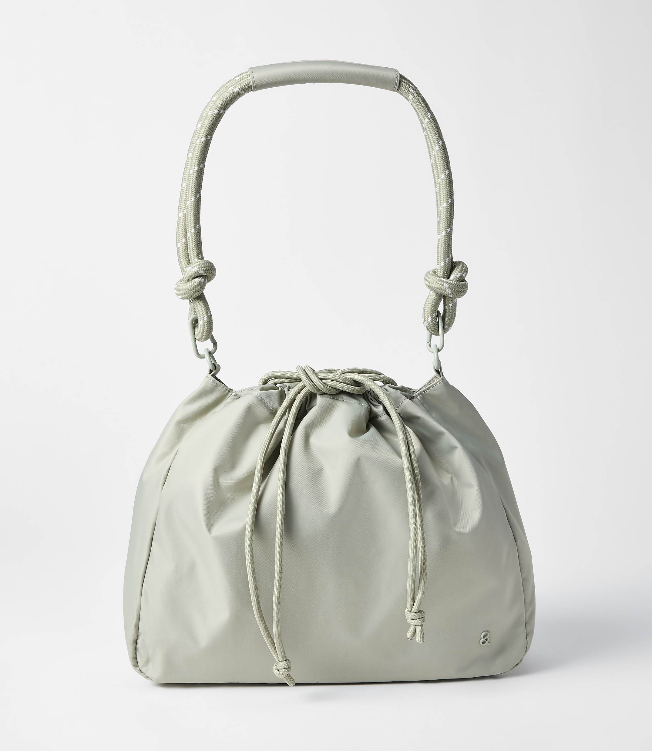 A light gray drawstring bag with a curved handle rests on a plain white background.