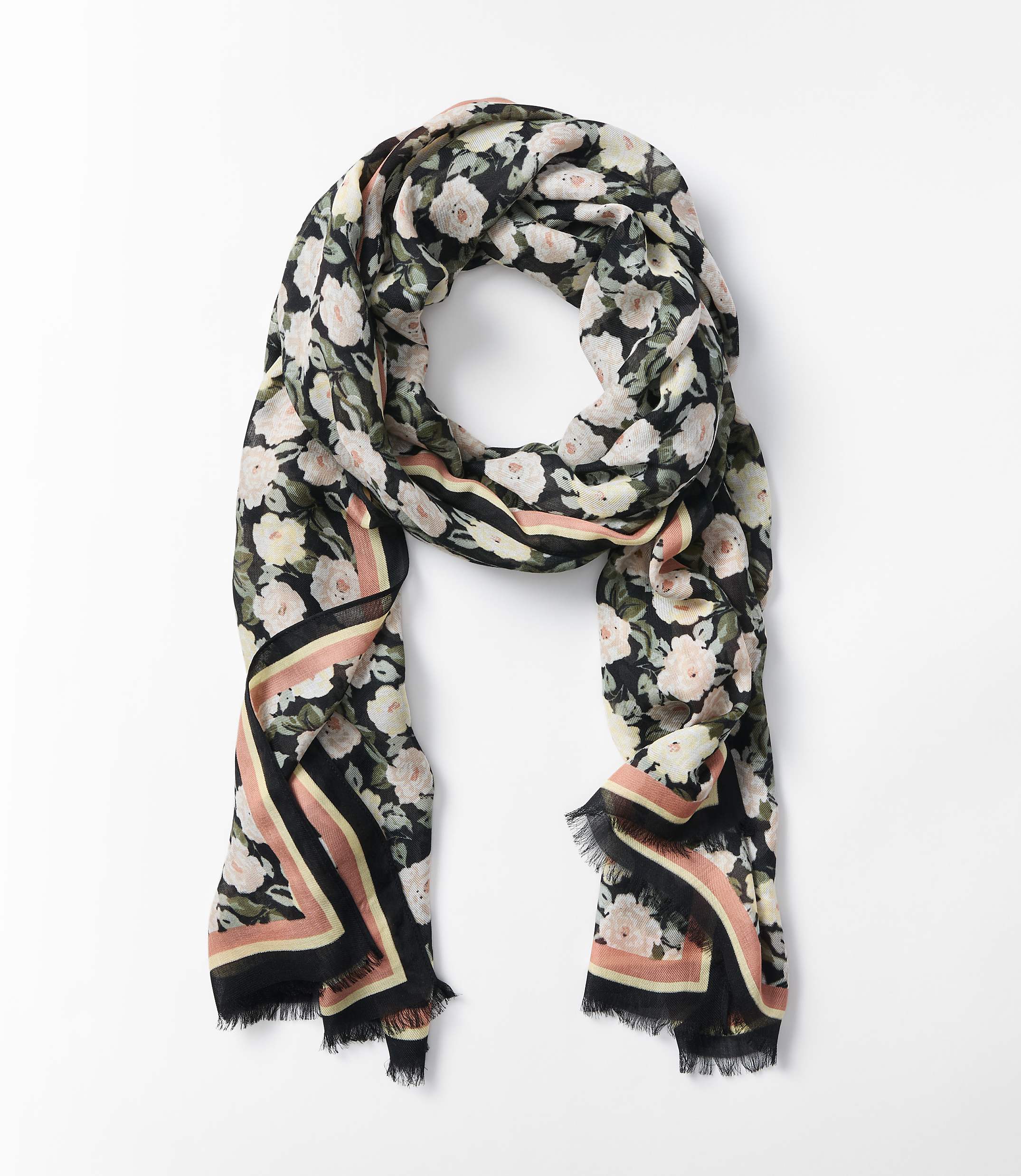 A floral scarf with a black background and pink roses is laid out on a white surface.