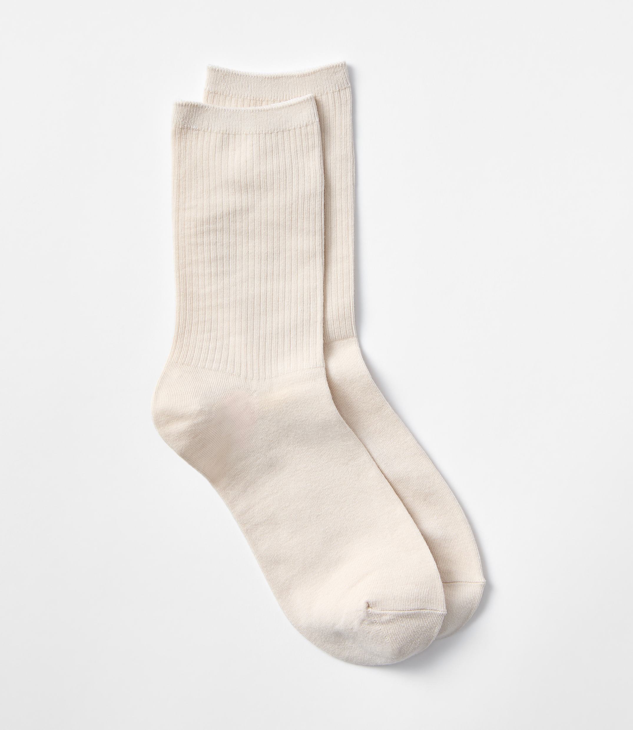 A pair of cream-colored ribbed socks rests on a plain white background.