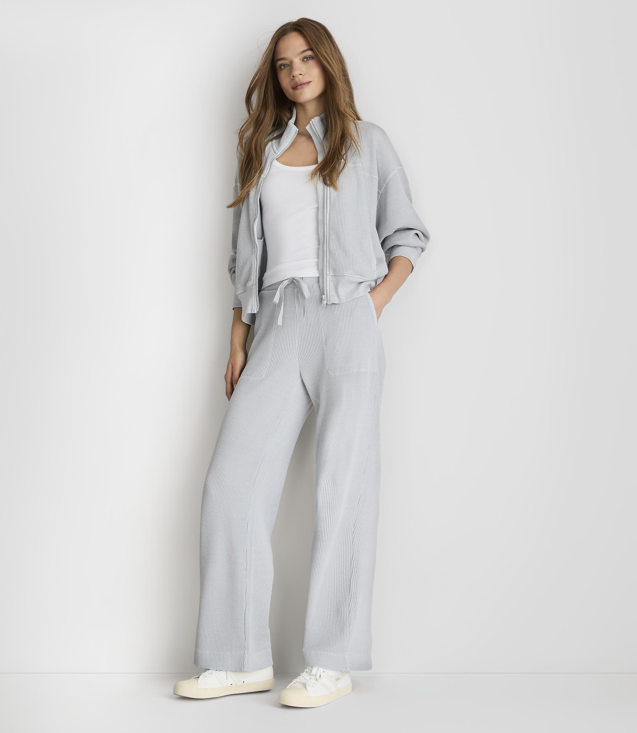 A woman in a light blue tracksuit stands against a plain white background.