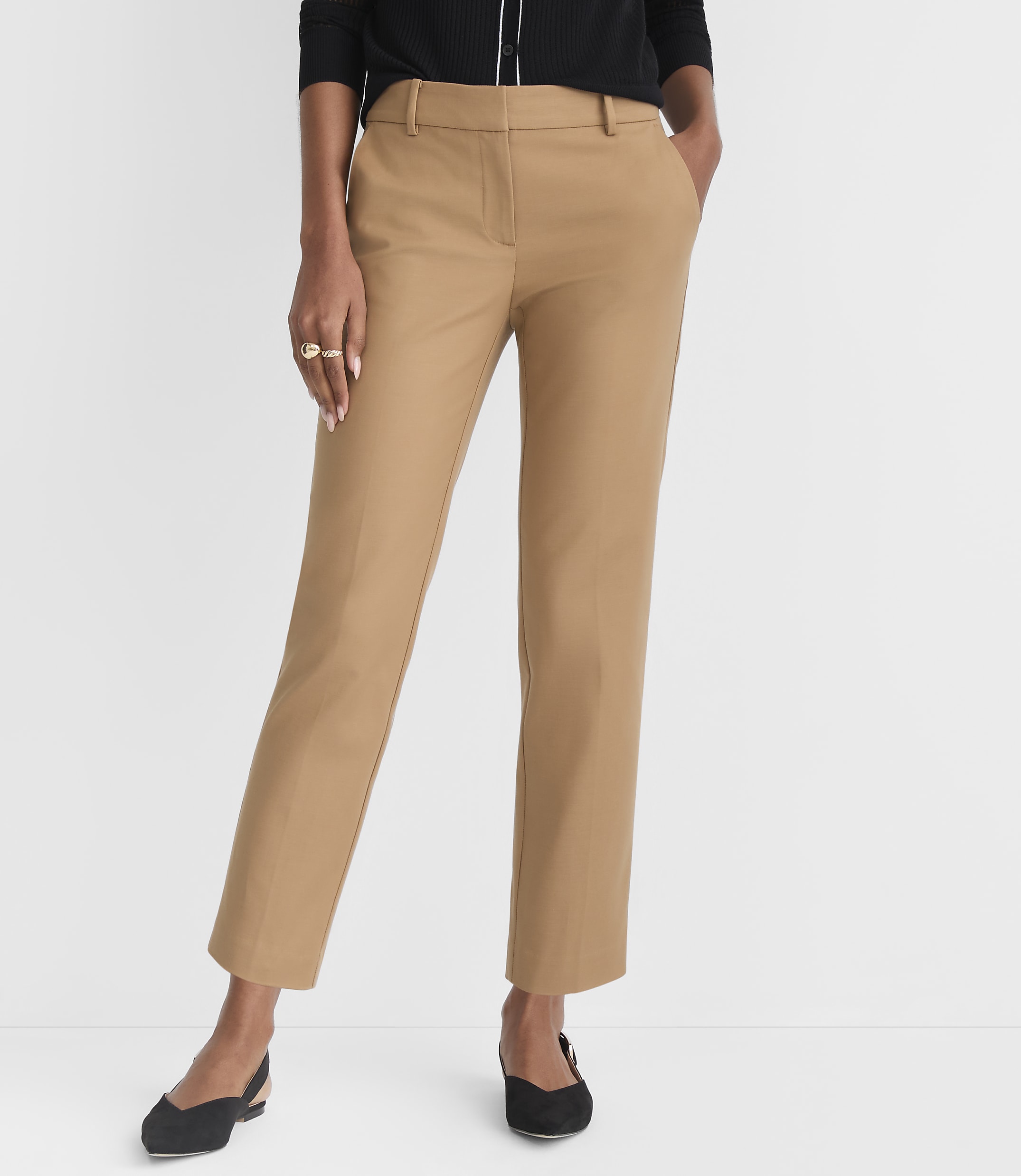 A person wearing tan pants and black flats stands against a plain white background.