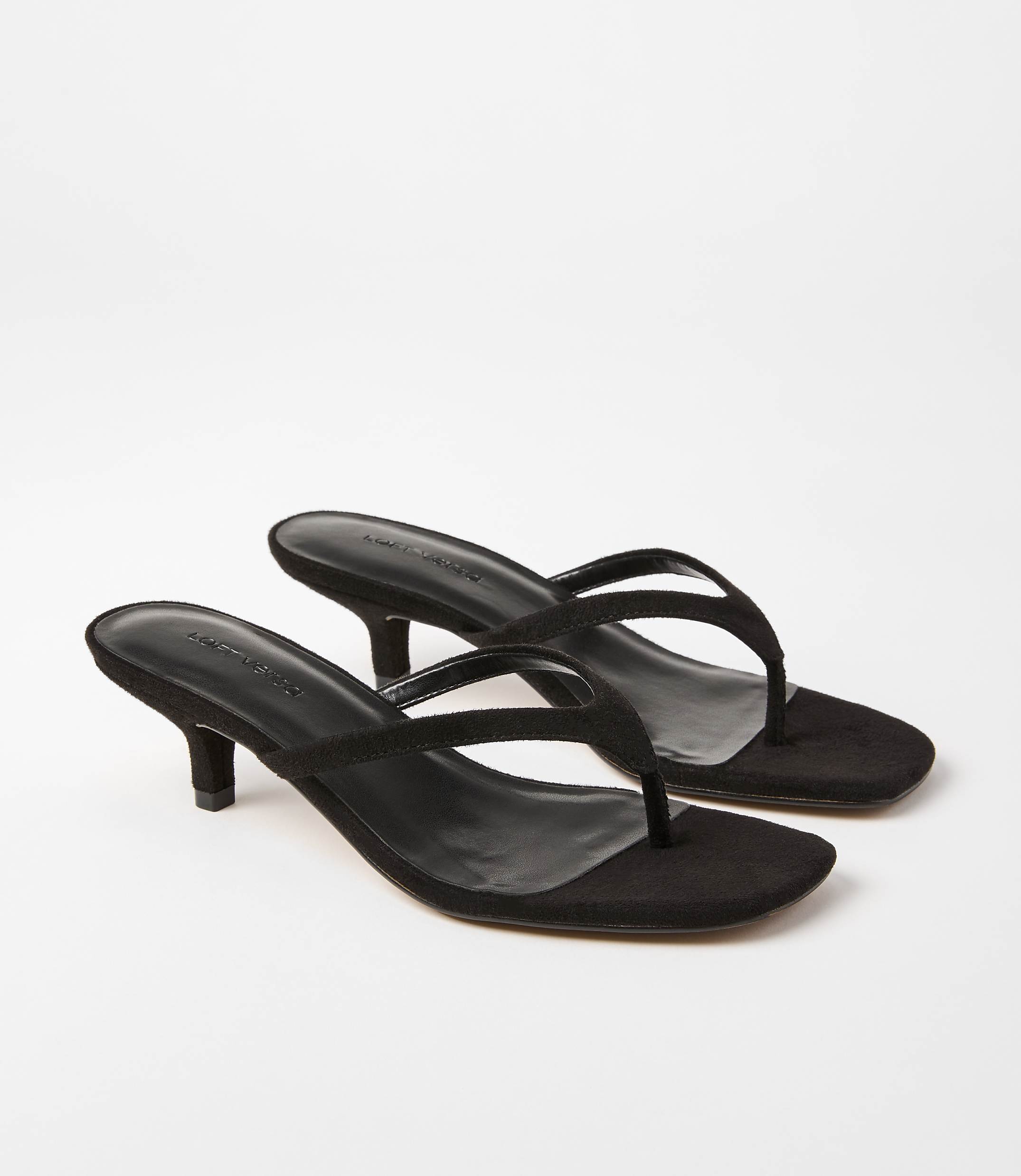 A pair of black suede thong sandals with kitten heels rests on a plain white background.