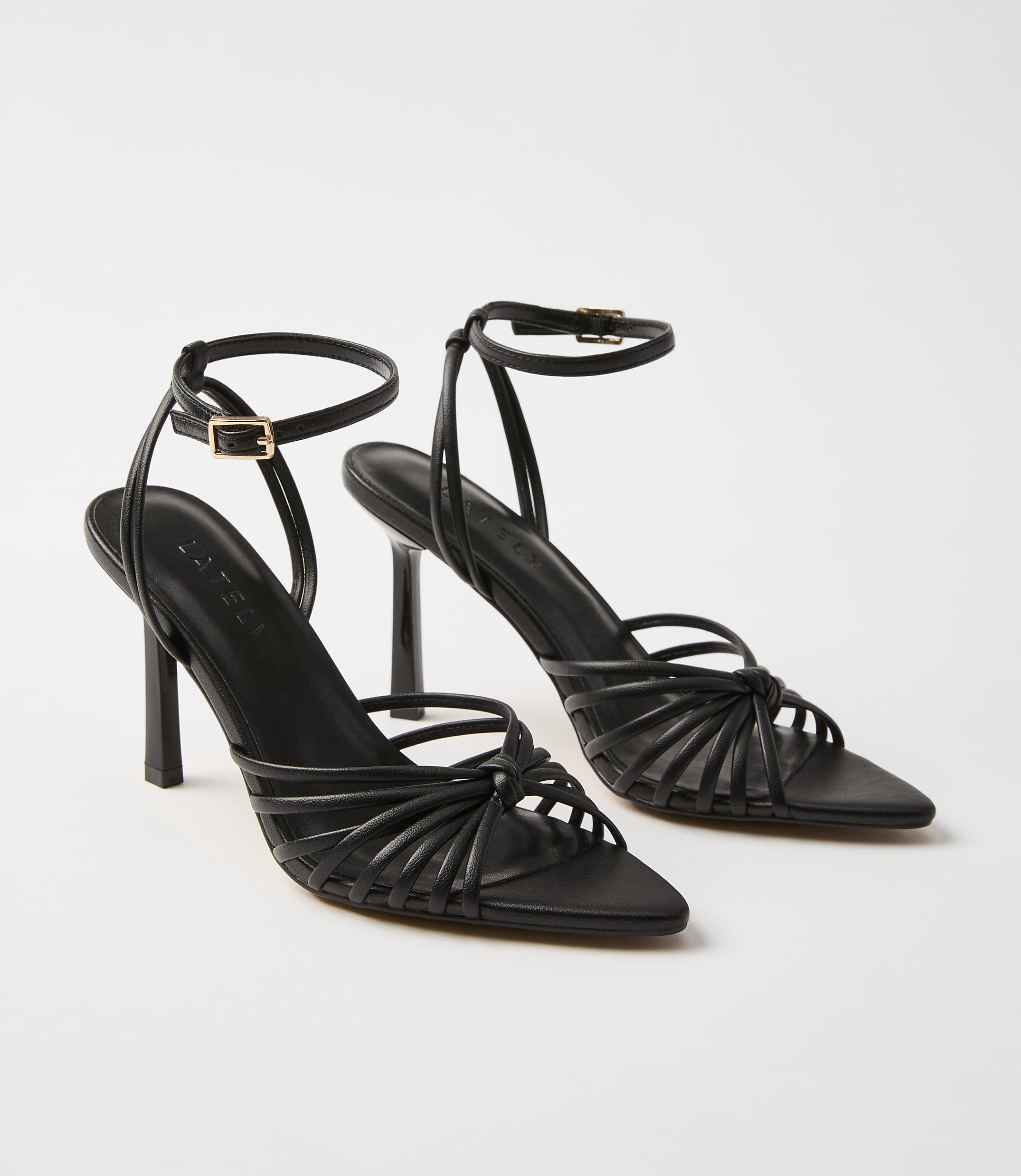 A pair of black strappy high-heeled sandals with ankle straps are displayed against a plain white background.