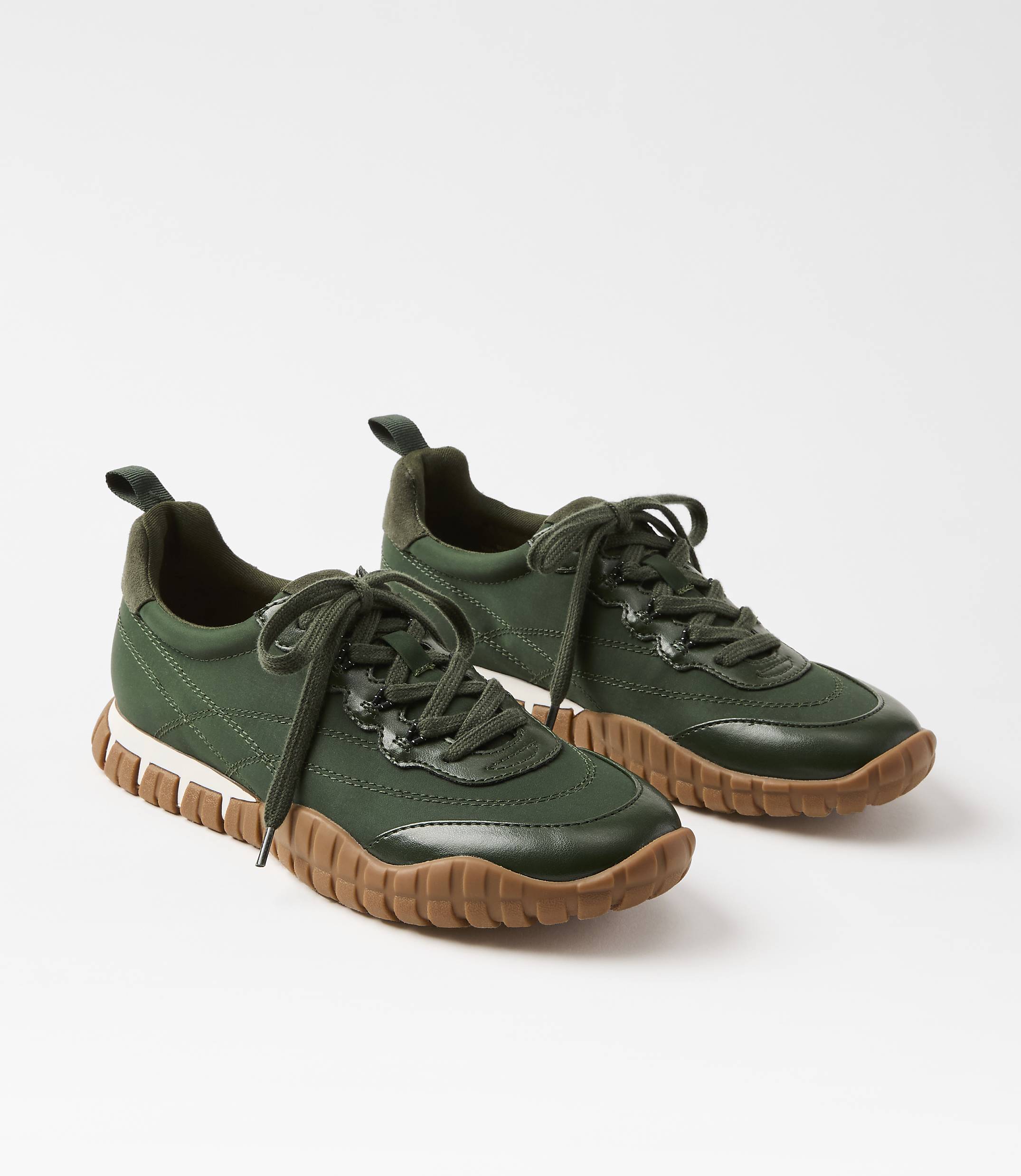A pair of green sneakers with brown soles rests on a white background.
