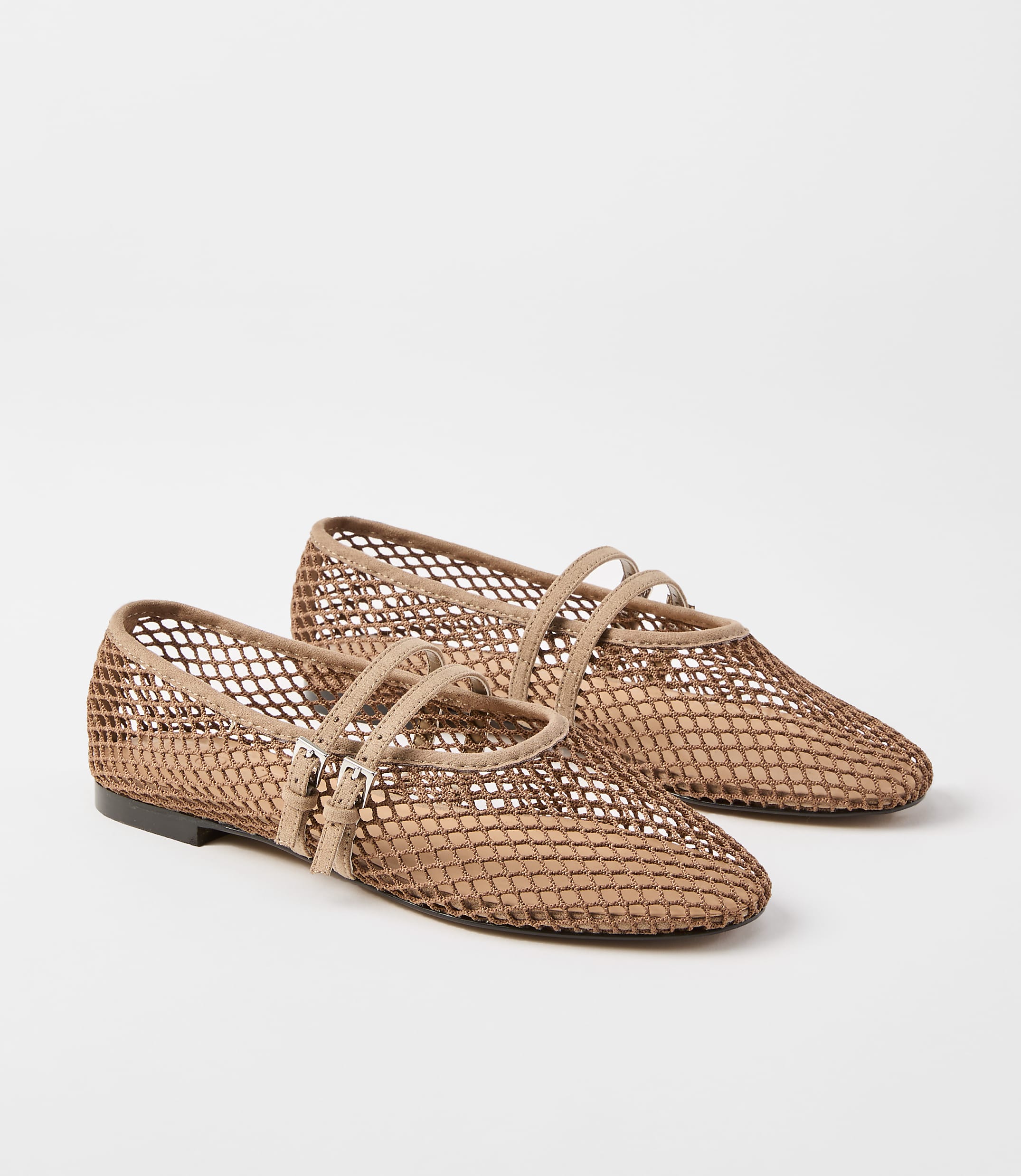A pair of tan mesh ballet flats with double straps and buckle closures rests on a plain white background.