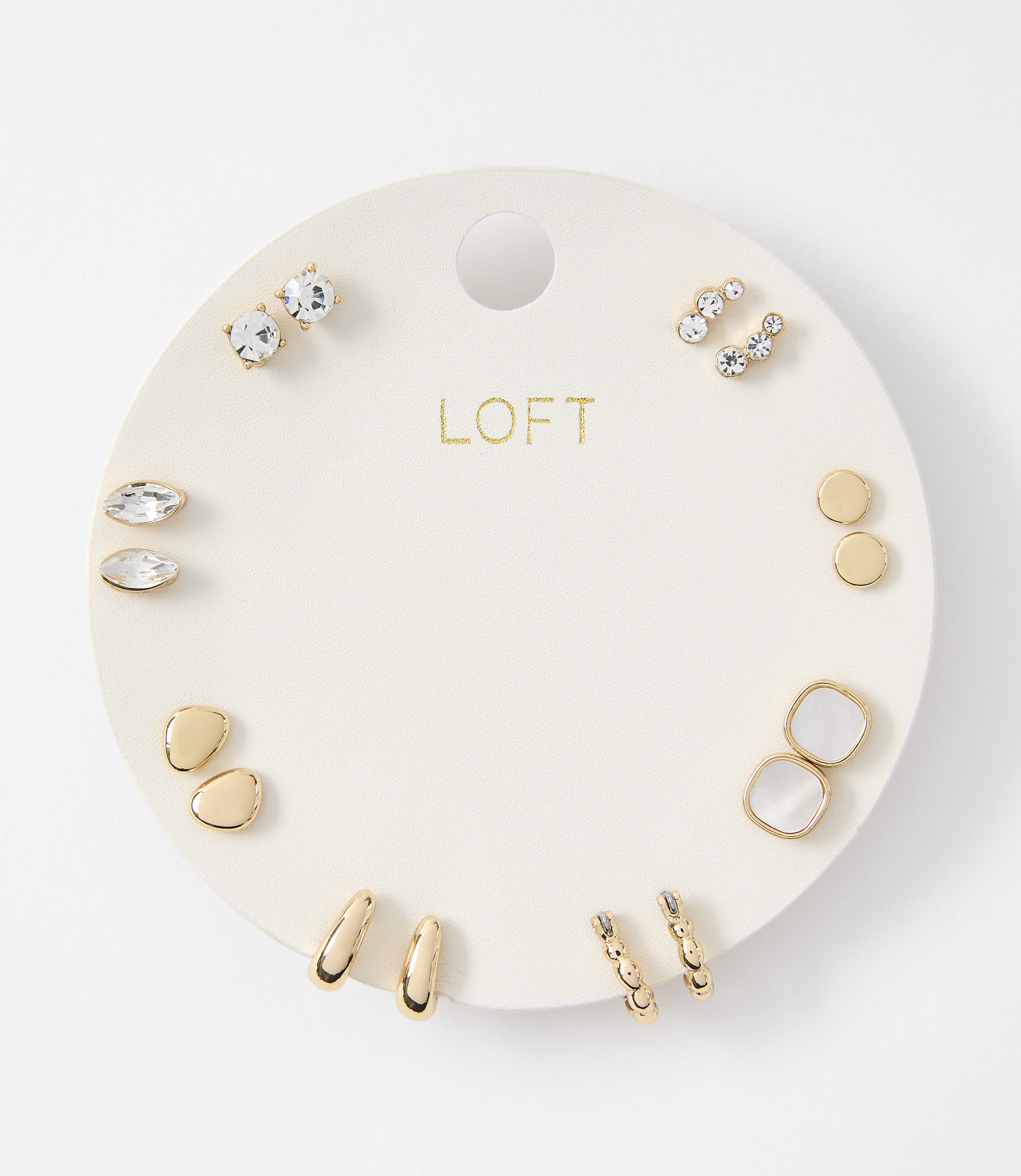 A collection of assorted gold and crystal earrings are displayed on a white circular card against a plain white background.