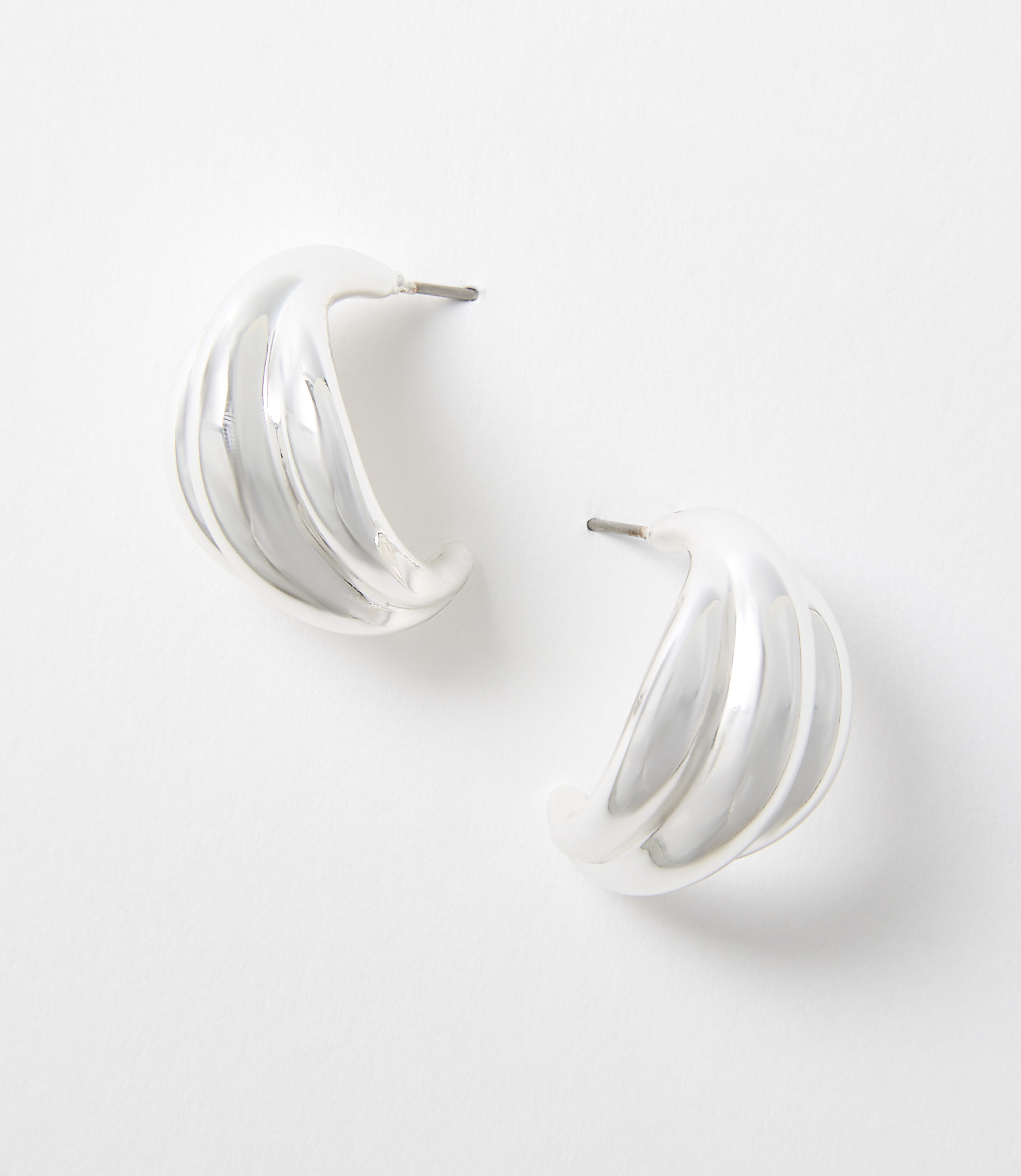 Two silver, ribbed hoop earrings rest on a plain white background.