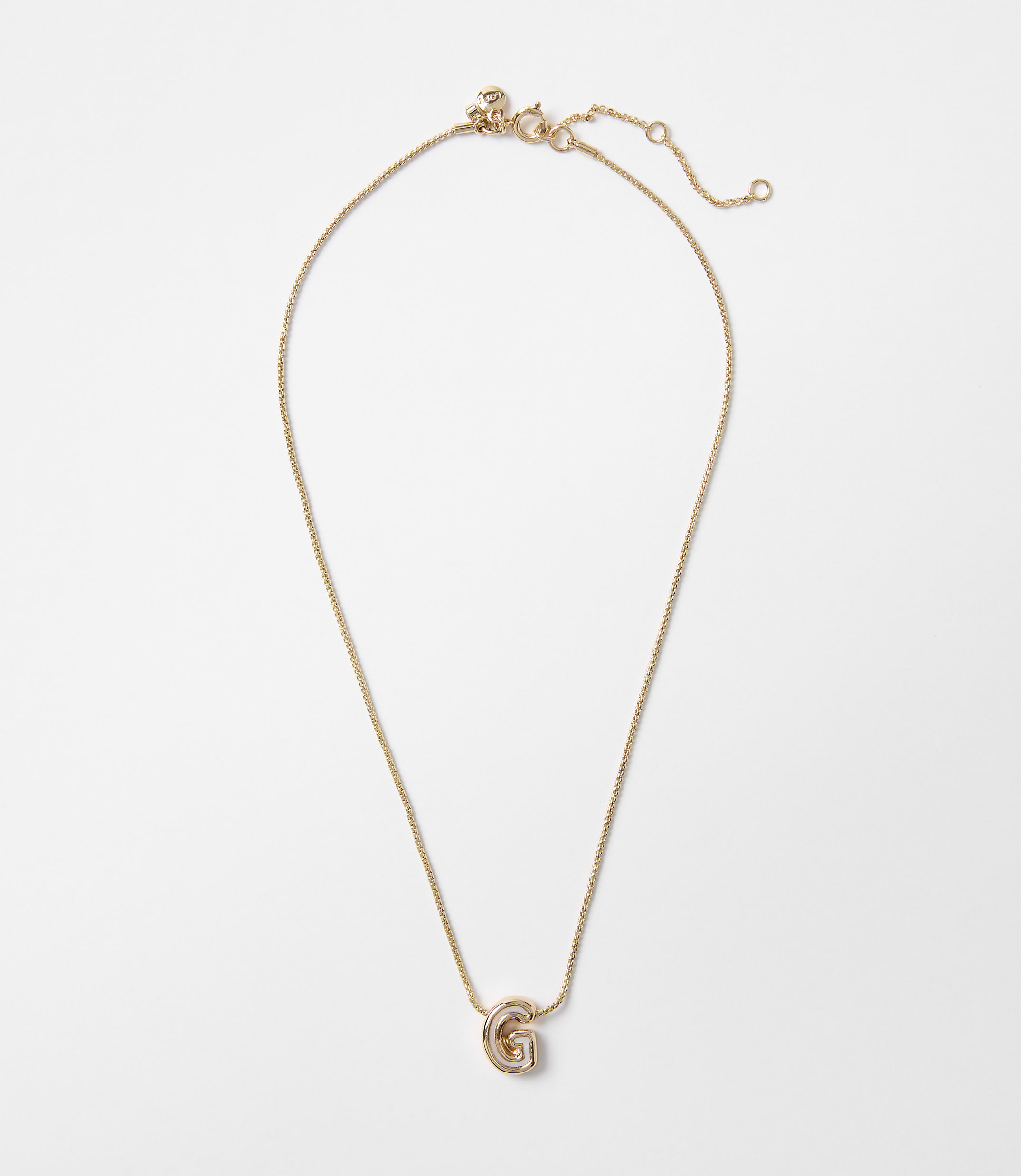 A delicate gold necklace with a "G" charm hangs against a plain white background.