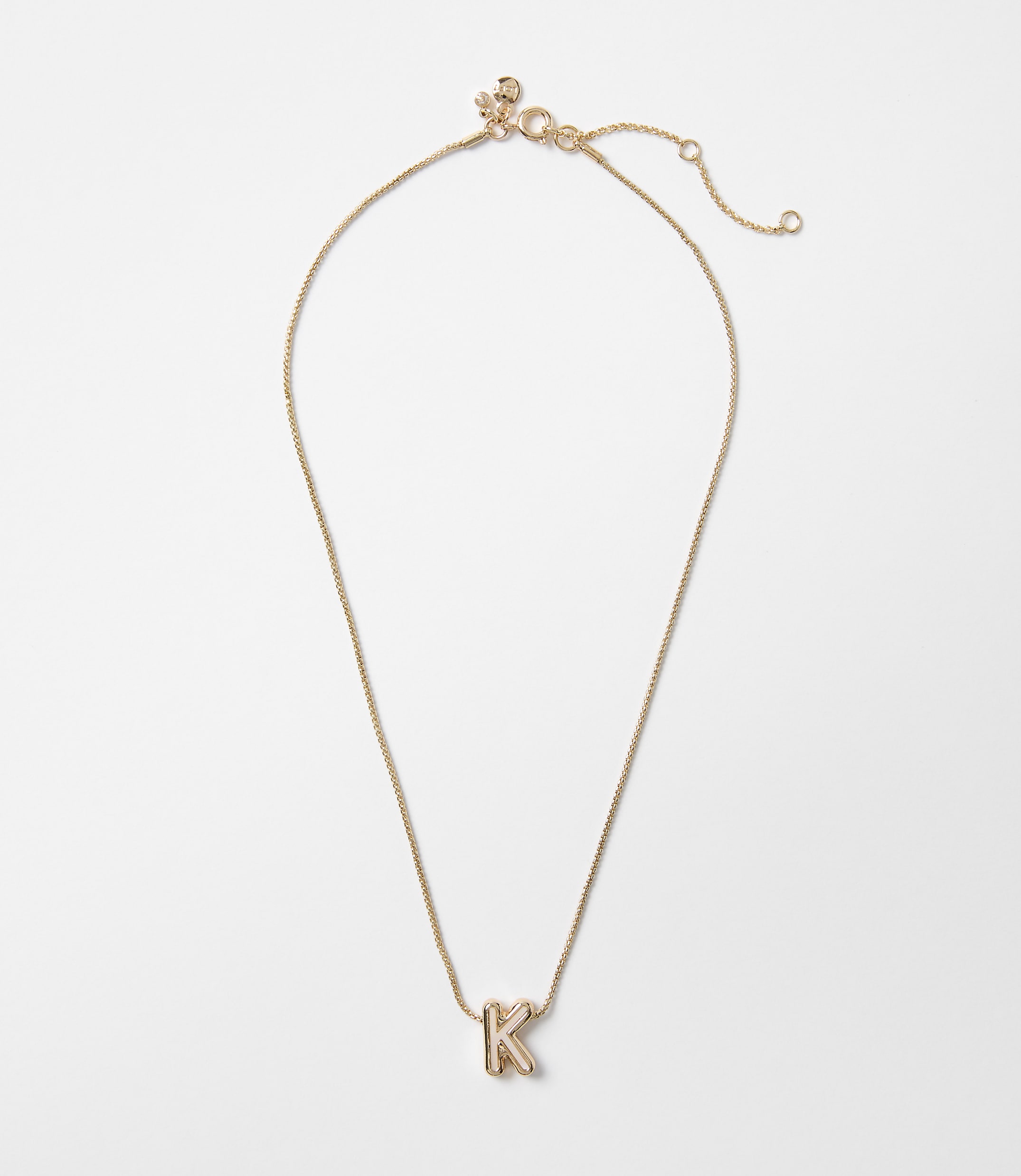 A delicate gold necklace with a letter "K" pendant rests on a plain white background.