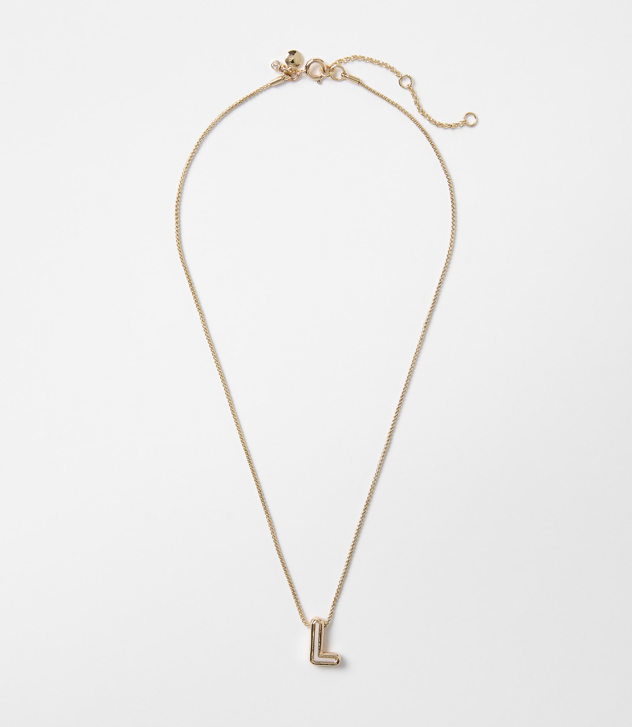 A delicate gold chain necklace with an "L" initial pendant hangs against a plain white background.