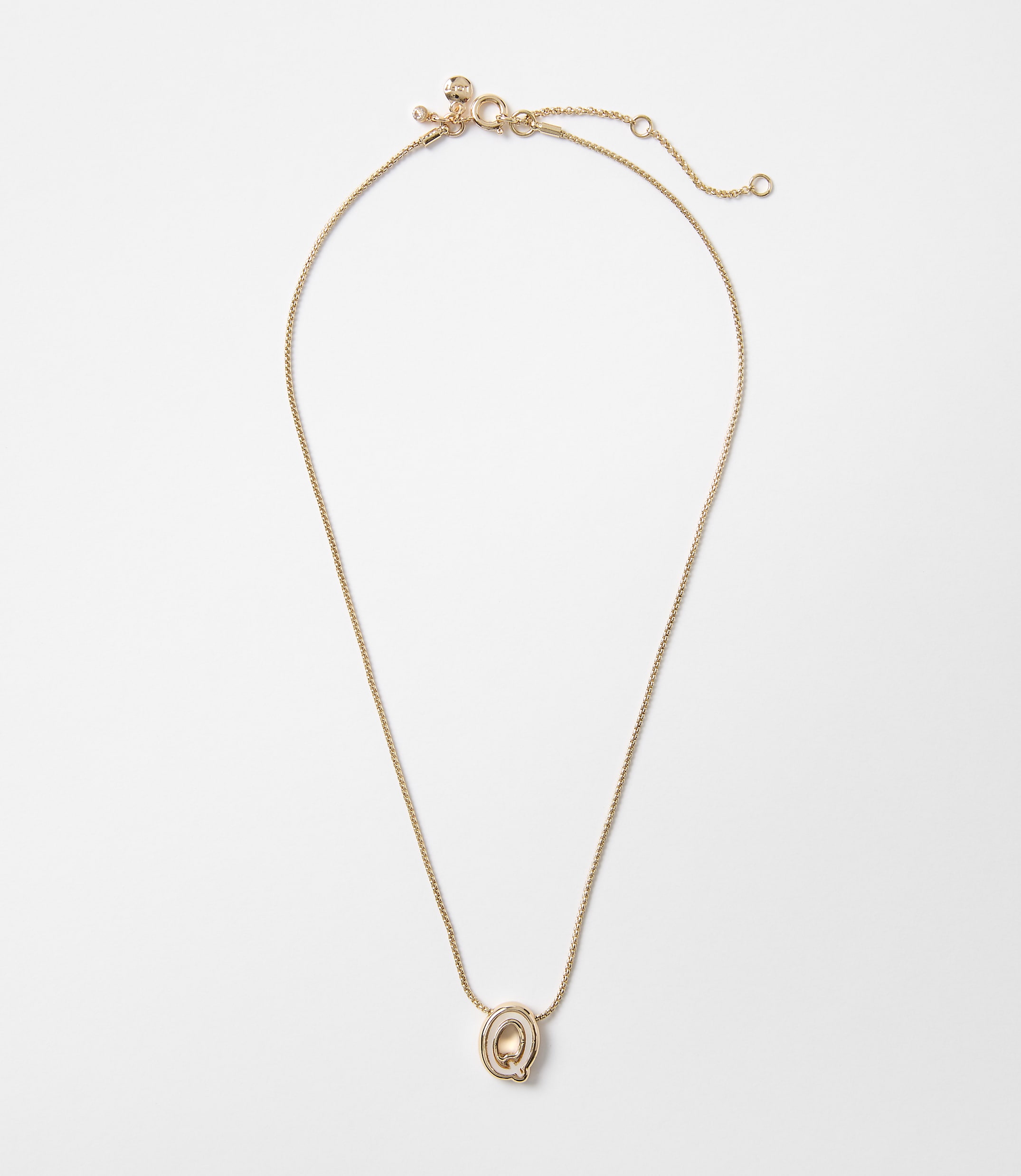 A delicate rose gold necklace with a small, oval pendant hangs against a plain white background.