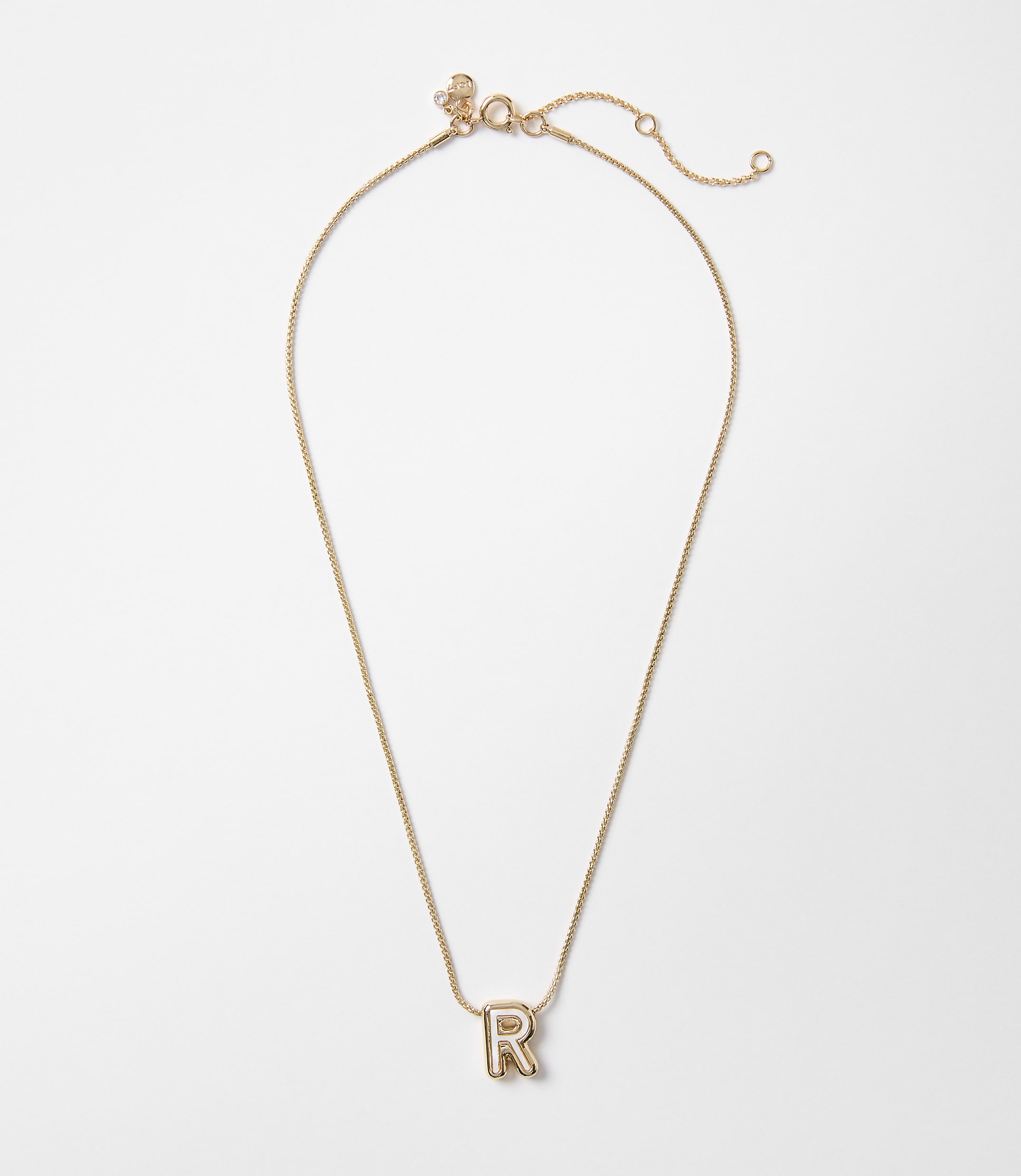 A delicate rose gold chain necklace with a single letter "R" pendant rests on a plain white background.