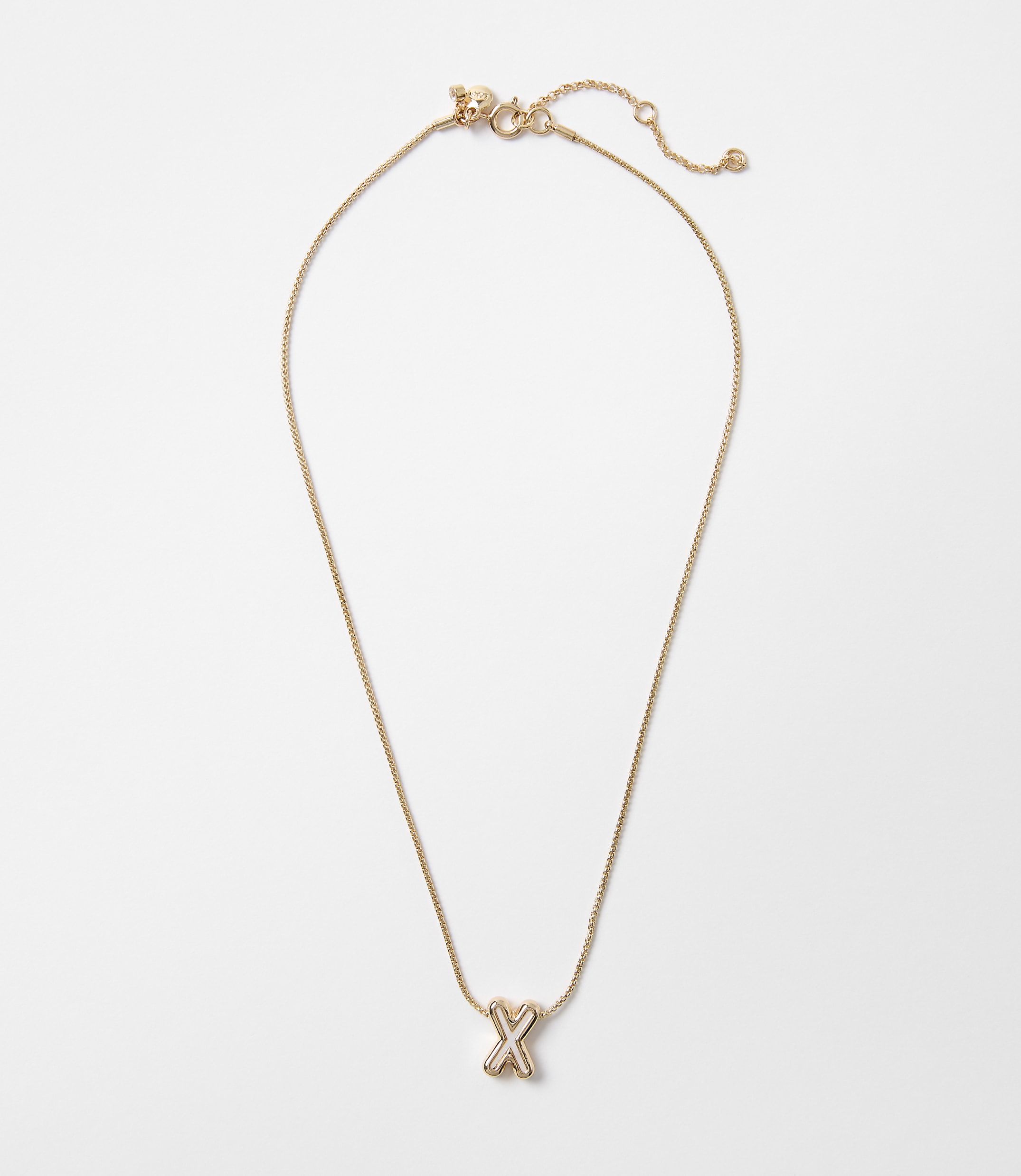 A delicate gold necklace with an "X" charm hangs against a plain white background.