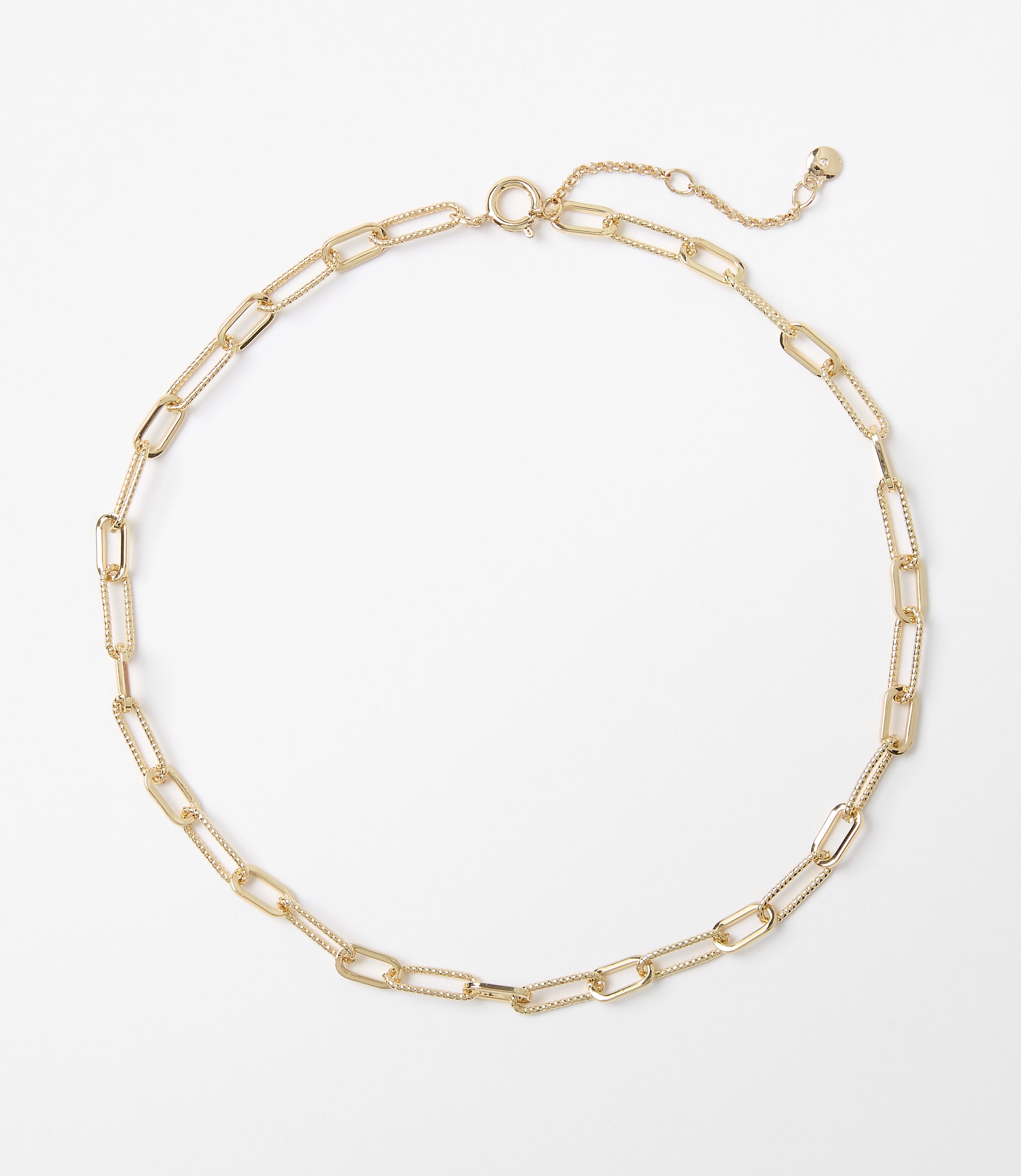 A delicate gold chain necklace with elongated oval links rests on a plain white background.