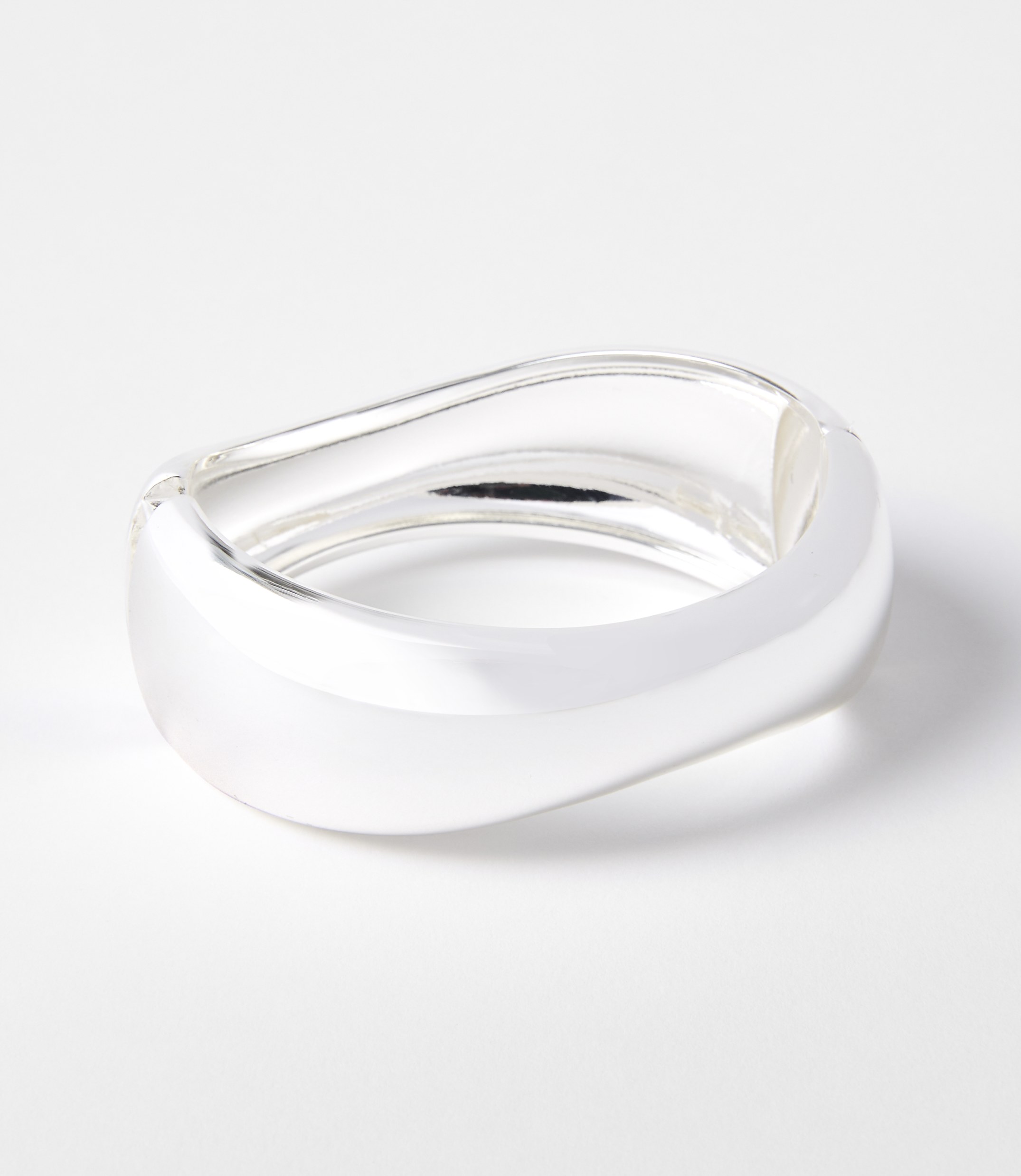 A sleek, silver, wavy bracelet rests on a clean white background.