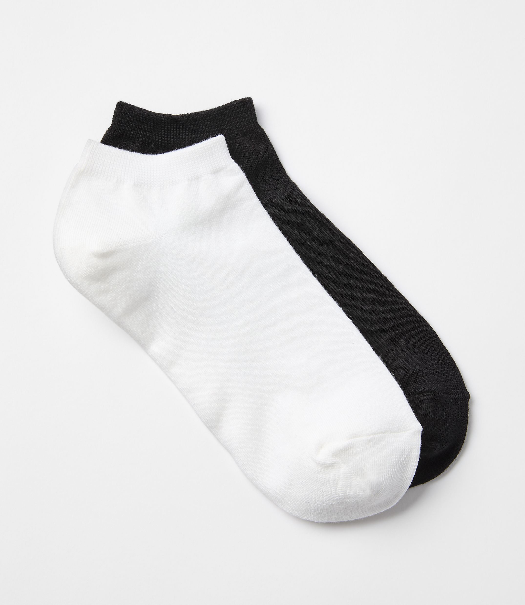 A white and black ankle sock lie side-by-side on a plain white background.