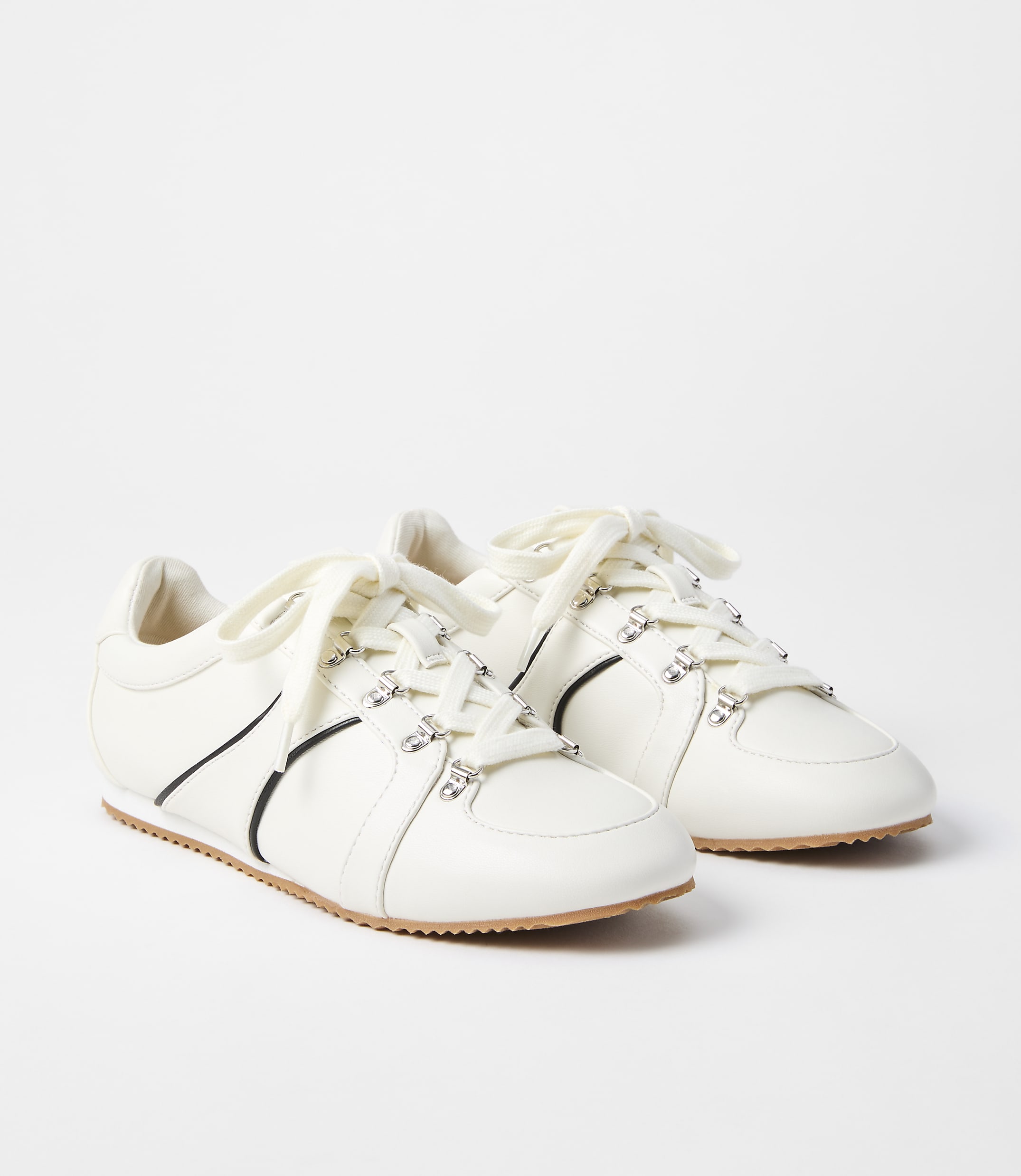 A pair of white leather sneakers with crystal embellishments and black accents are displayed against a plain white background.