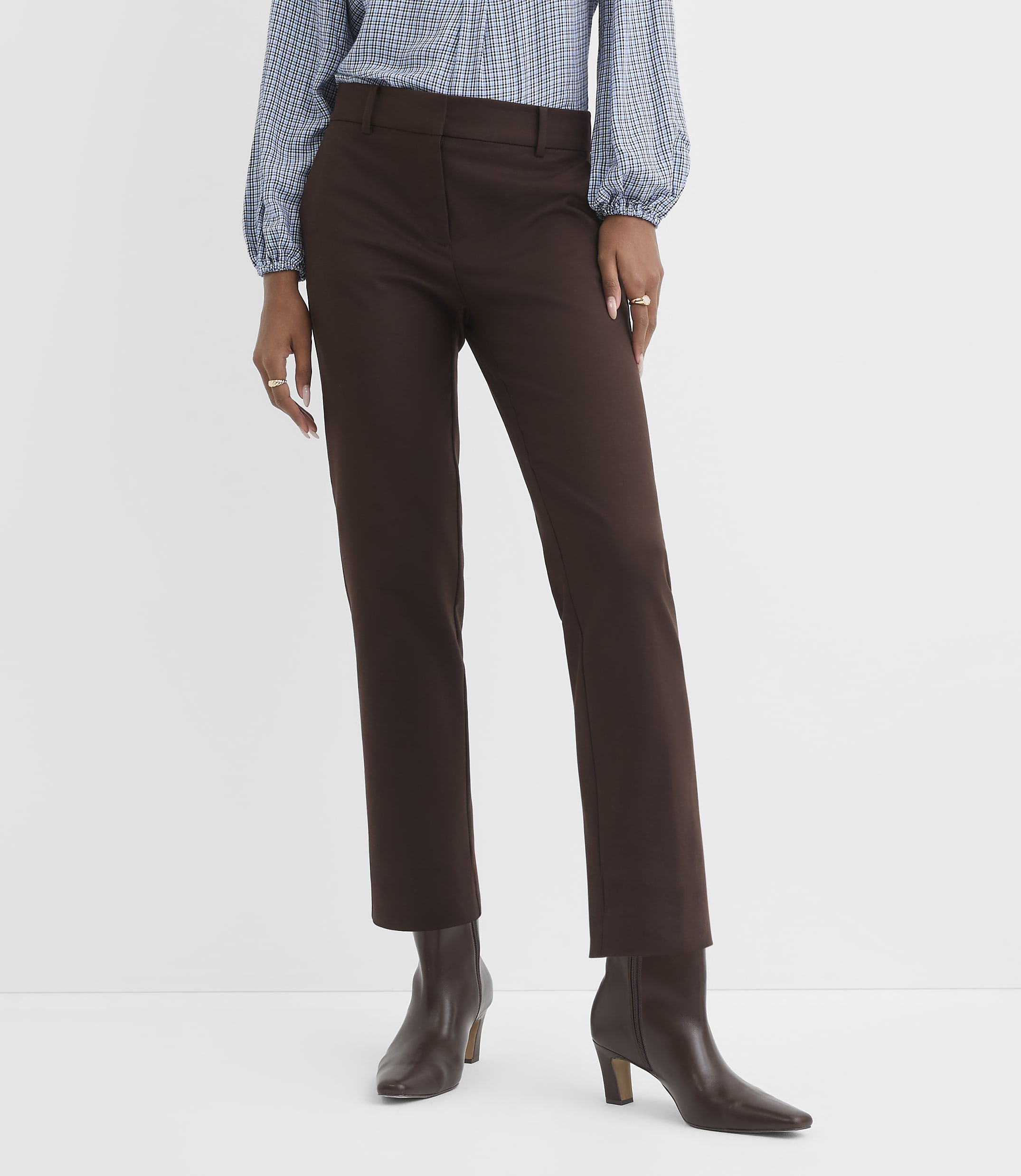 A person stands in brown pants and boots against a plain white background.