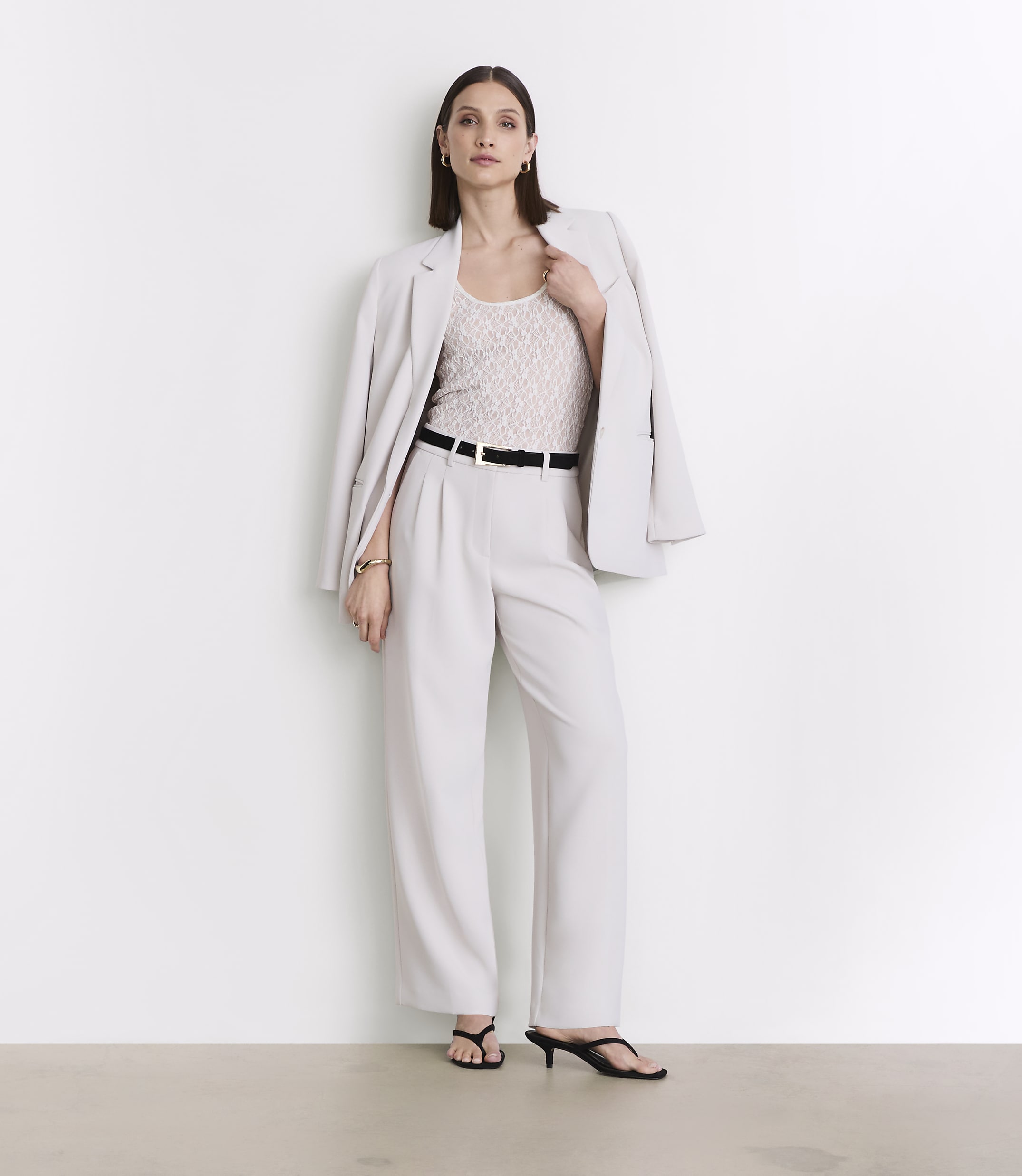 A woman in a light-colored suit stands against a plain white background.