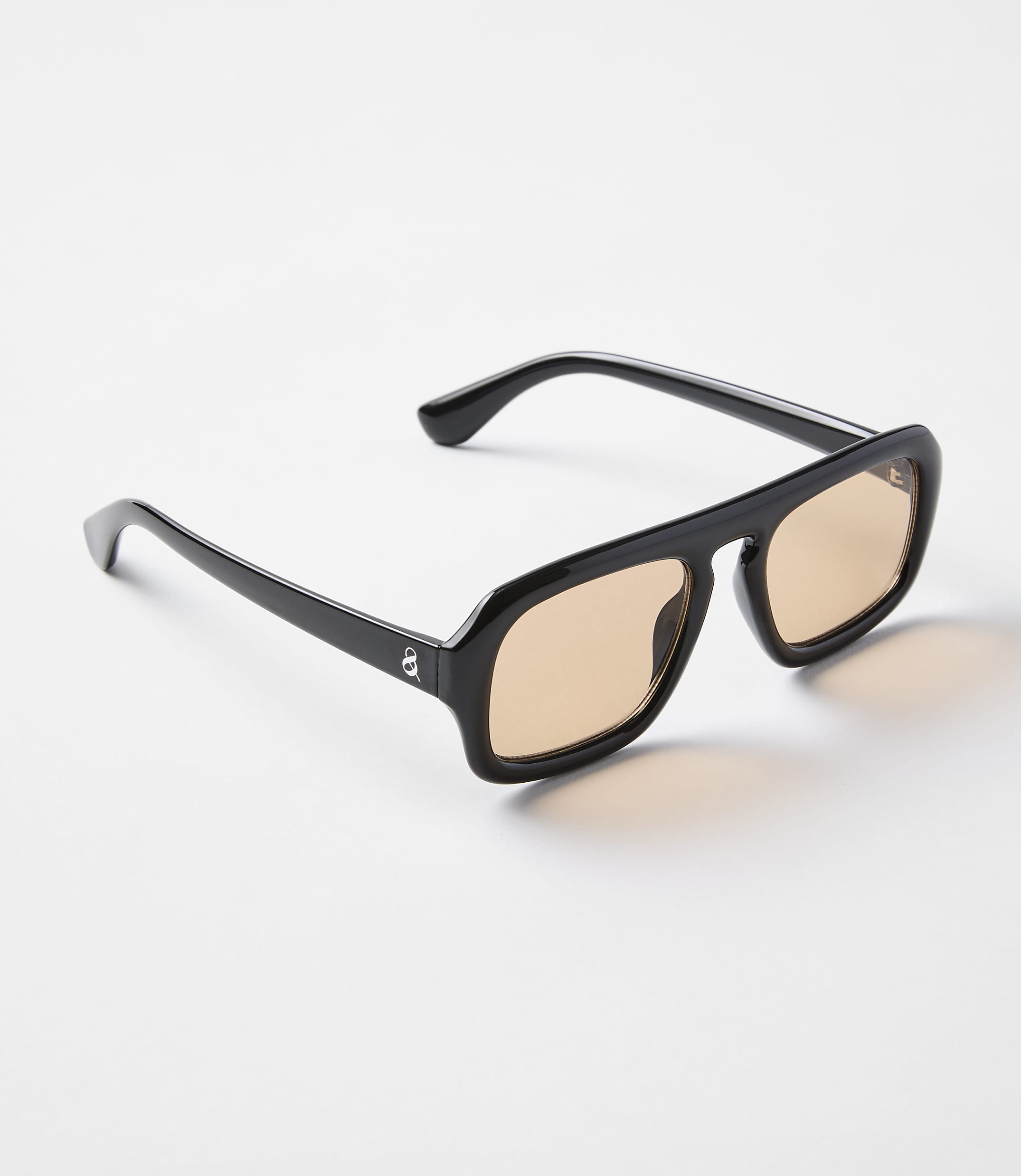 A pair of black-framed sunglasses with amber lenses rests on a plain white background.
