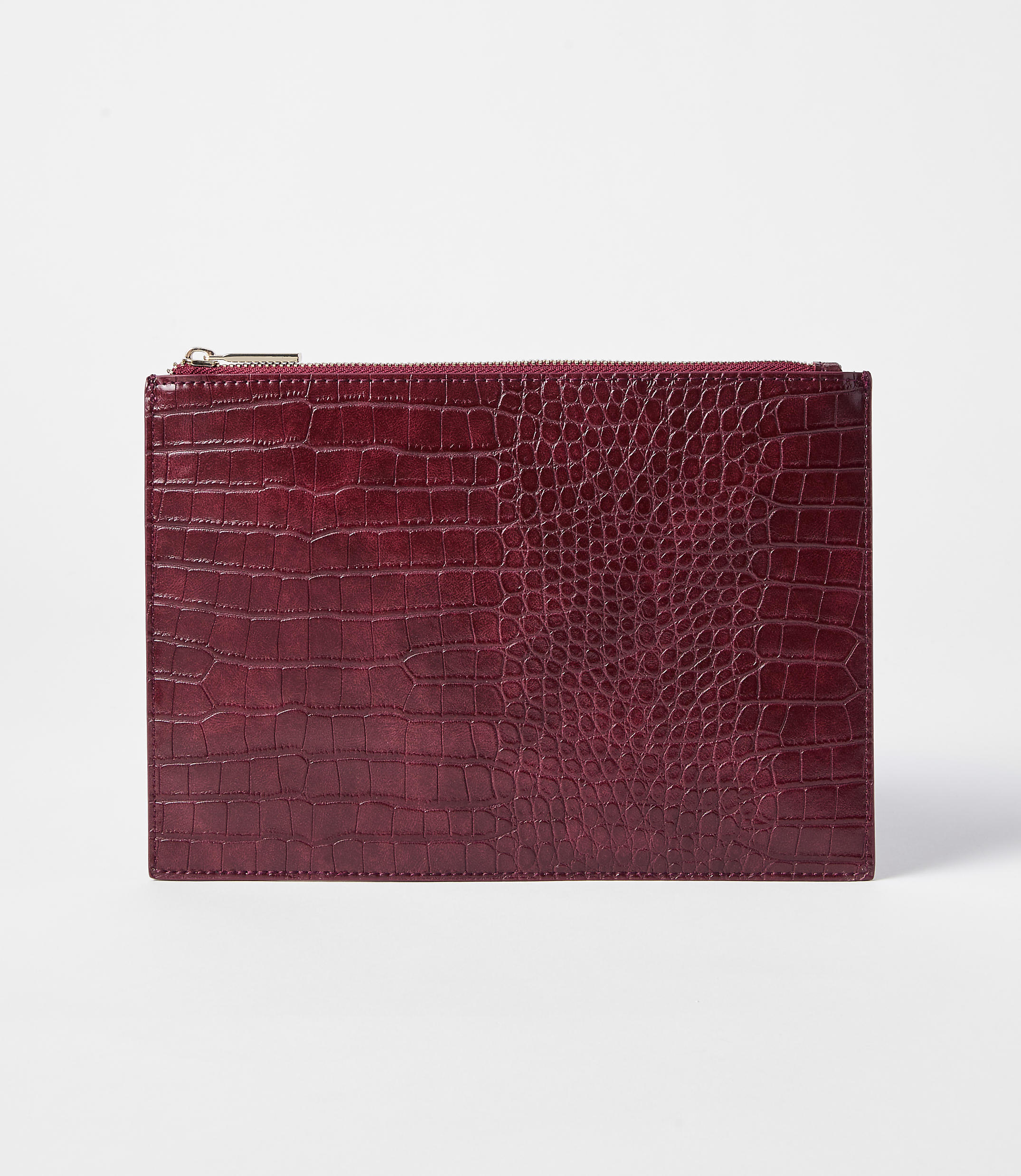 A deep red, crocodile-embossed clutch with a gold zipper rests on a plain white background.