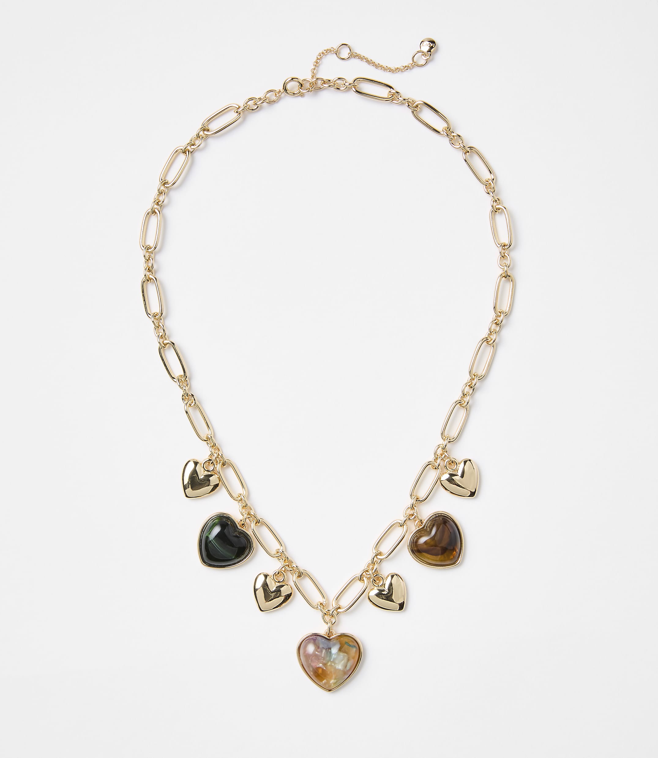 A gold chain necklace with multiple heart-shaped charms, some metallic and others iridescent, rests against a plain white background.