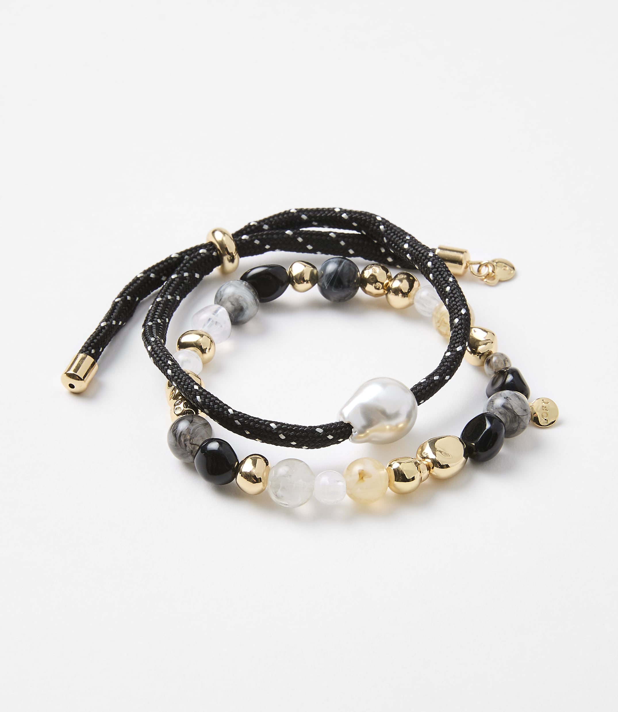 Two beaded bracelets, one with a black cord and white dots, are arranged on a plain white background.