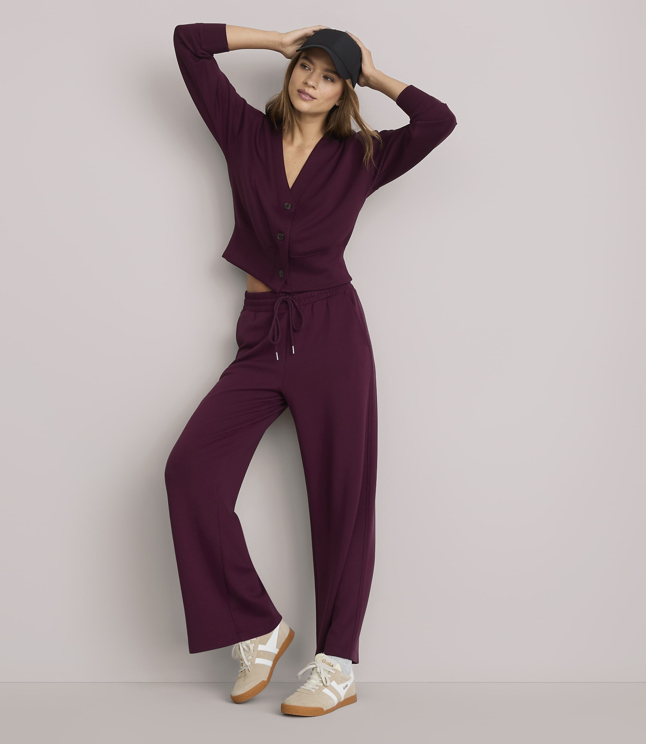 A woman in a burgundy cardigan and matching wide-leg pants poses against a plain white background.