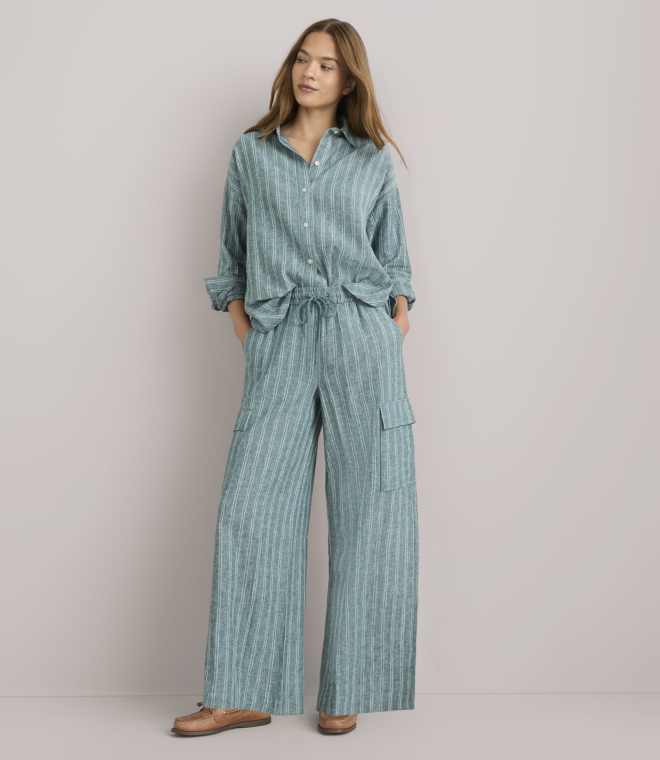 A woman in a striped teal pajama set stands against a plain white background.