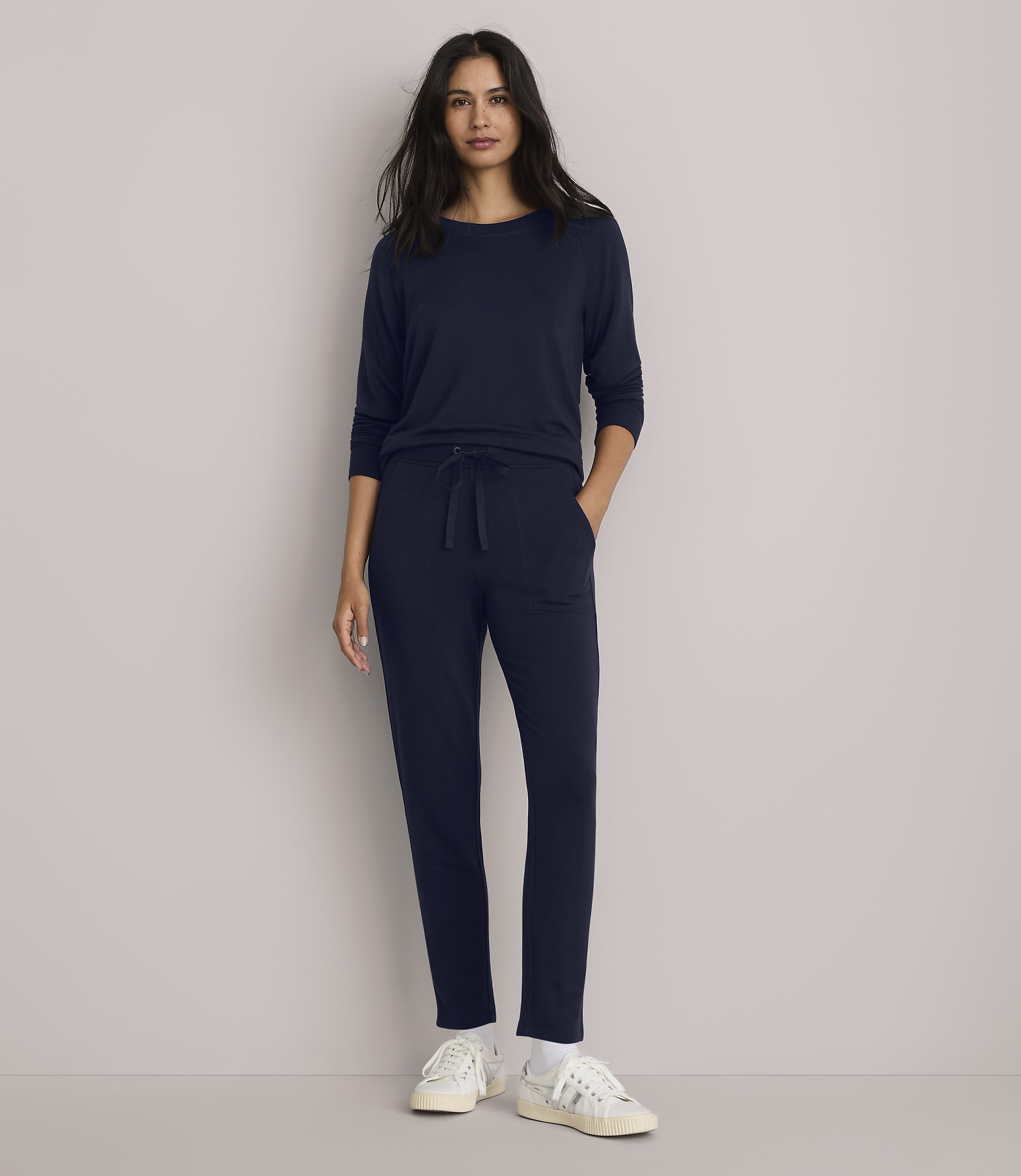 A woman in a navy blue loungewear set stands against a plain gray background.