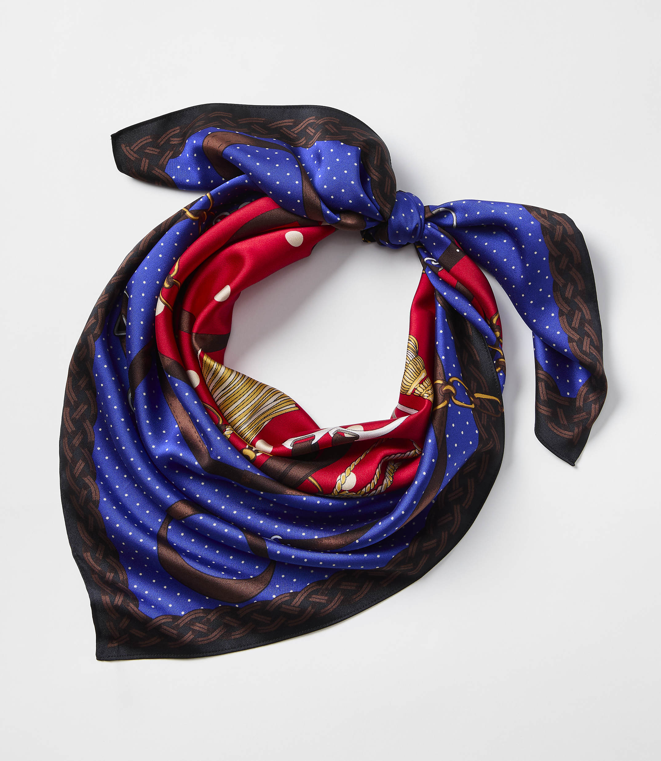 A vibrant silk scarf with a nautical print is tied in a knot against a plain white background.