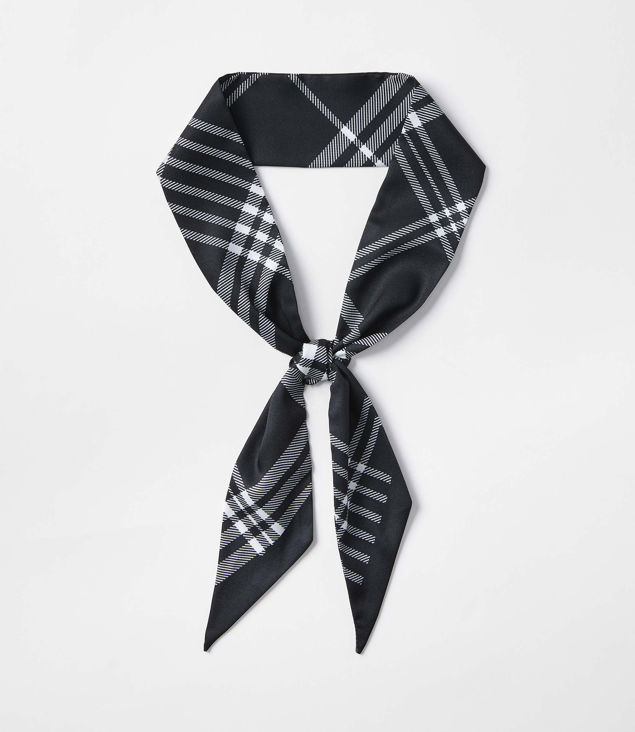 A black and white plaid scarf is tied in a knot in the foreground against a plain white background.