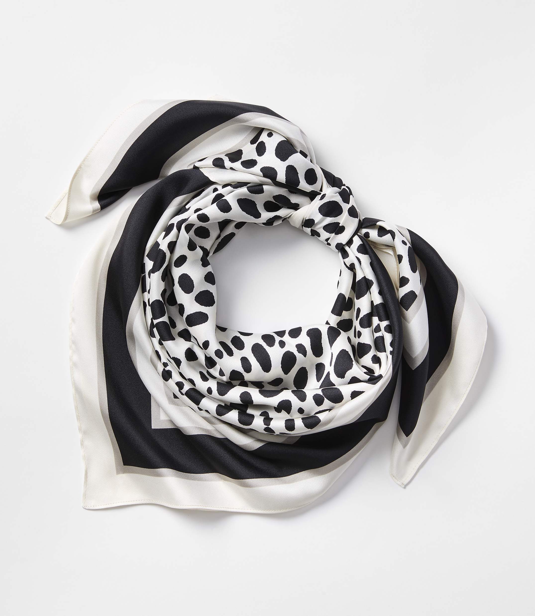 A black, white, and grey patterned silk scarf is neatly folded against a plain white background.