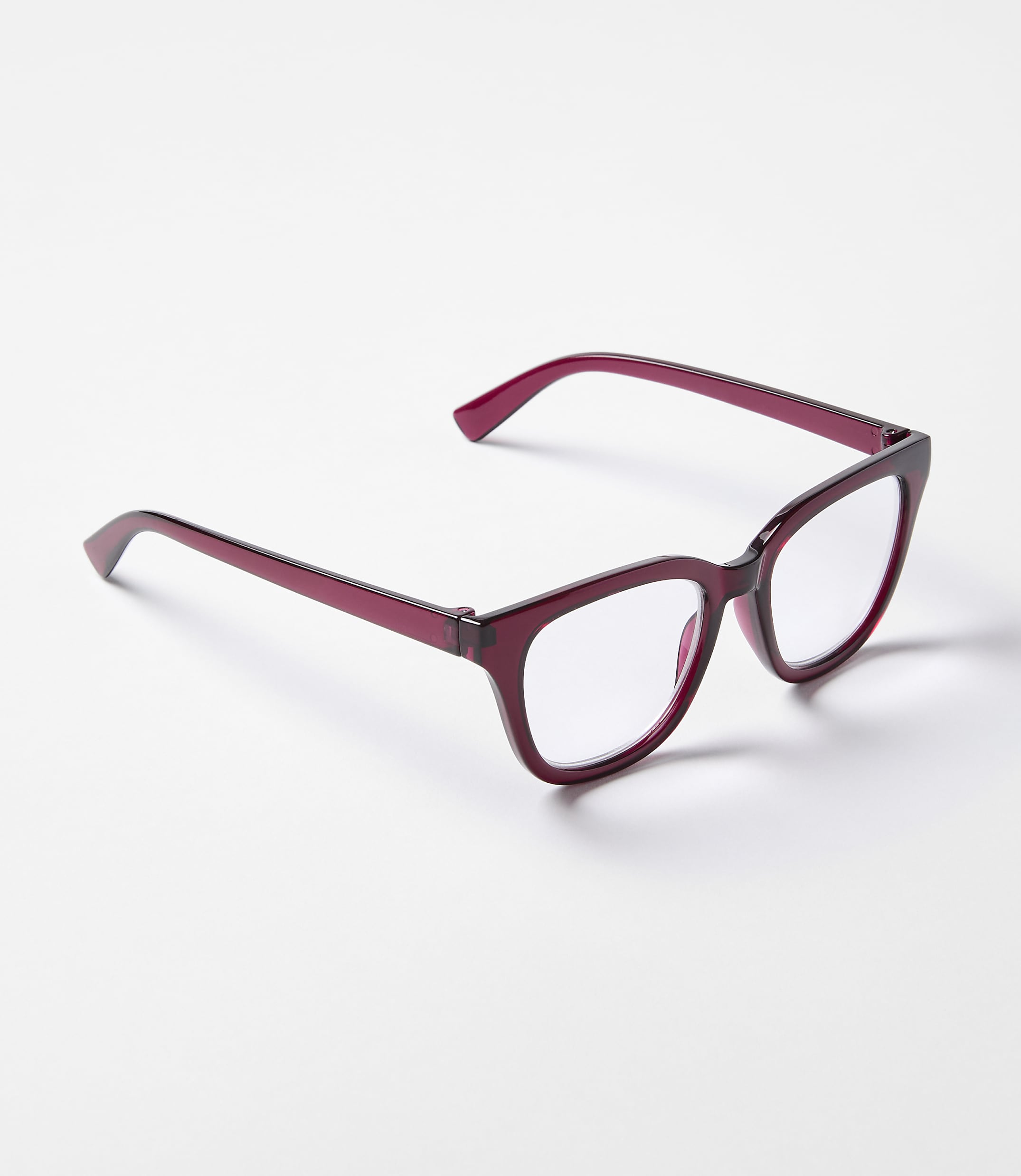 A pair of deep red, square-framed glasses rests on a plain white surface.