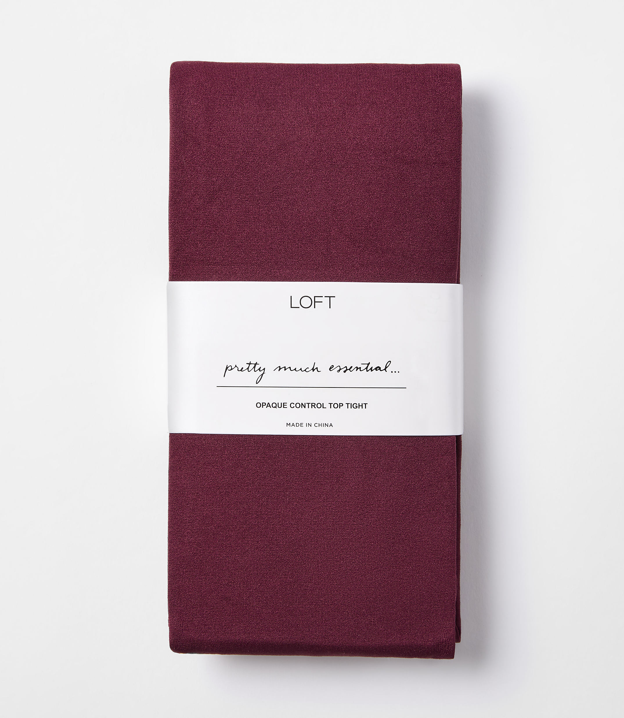 A folded pair of burgundy opaque control top tights with a white band displaying the brand "LOFT" and product details is presented against a plain white background.