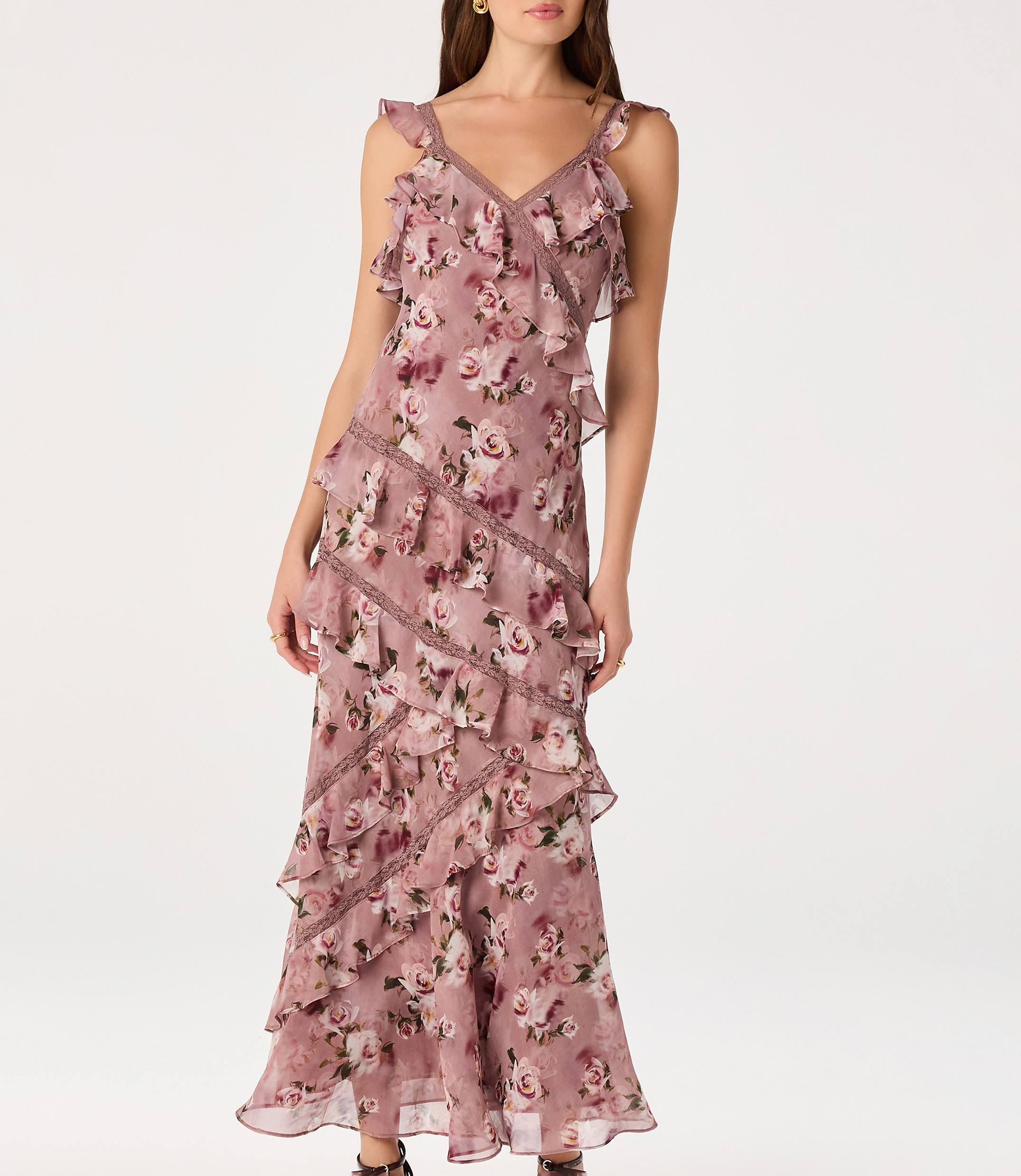 A woman in a ruffled, floral-print dress stands against a plain white background.