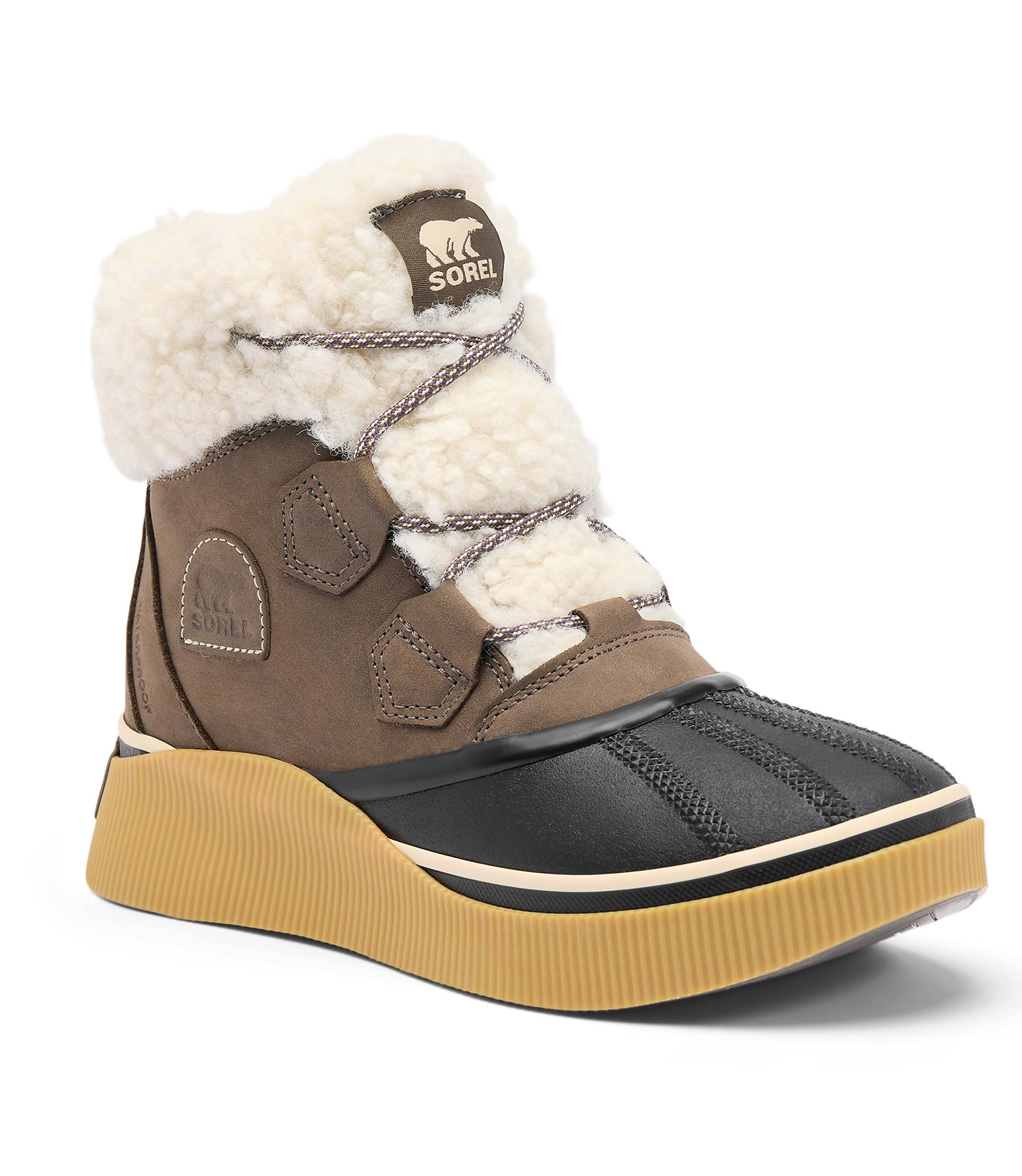 A brown Sorel boot with a white fluffy lining and a thick tan sole stands against a plain white background.