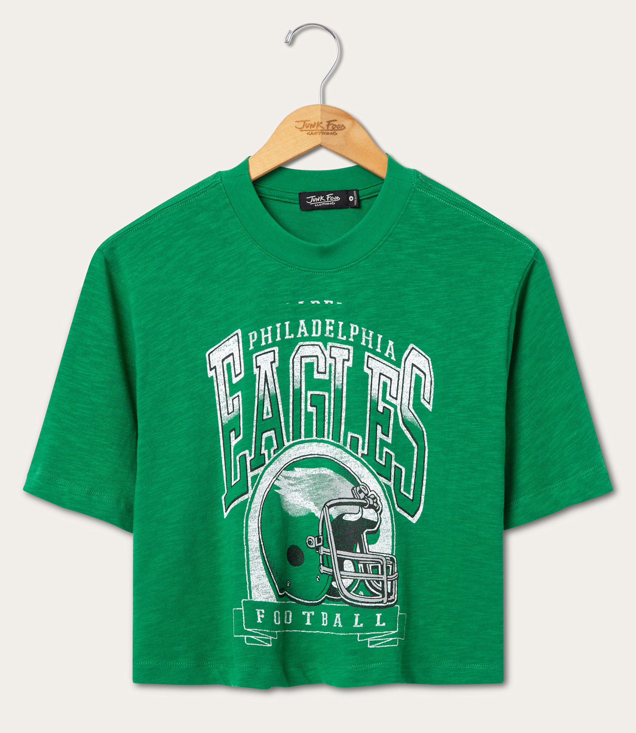 A green Philadelphia Eagles football t-shirt hangs on a wooden hanger against a plain white background.