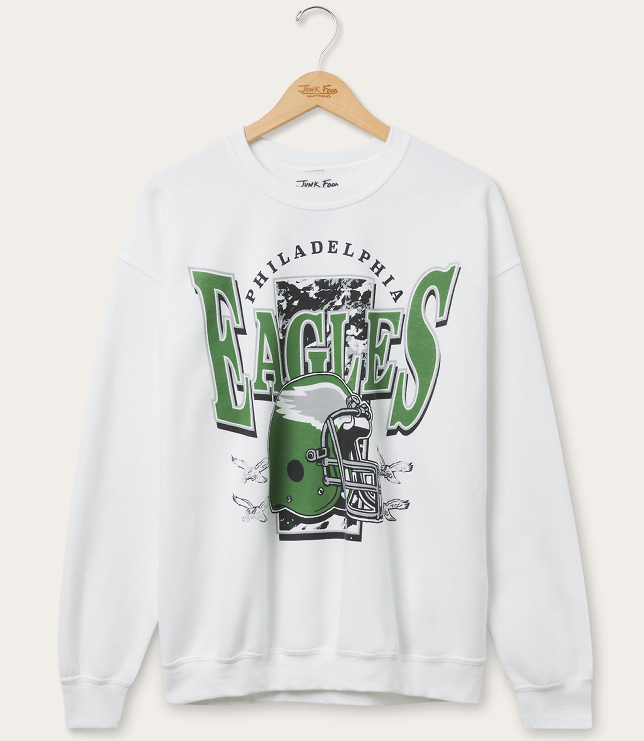 A white sweatshirt with a Philadelphia Eagles graphic featuring a helmet and lettering is displayed on a hanger against a plain white background.