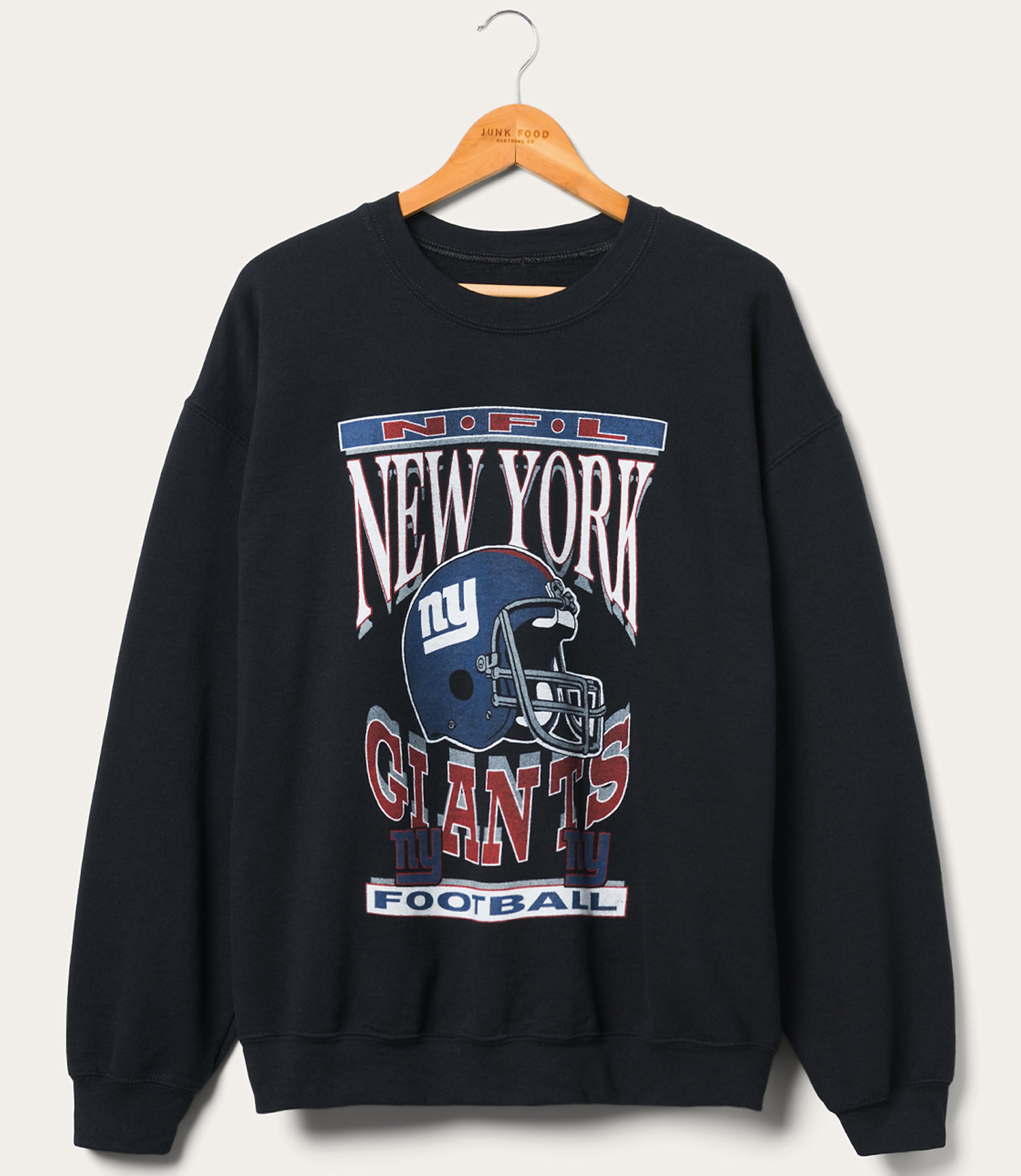 A dark blue New York Giants sweatshirt with a graphic of a helmet and team name is displayed on a wooden hanger against a plain, light-colored background.