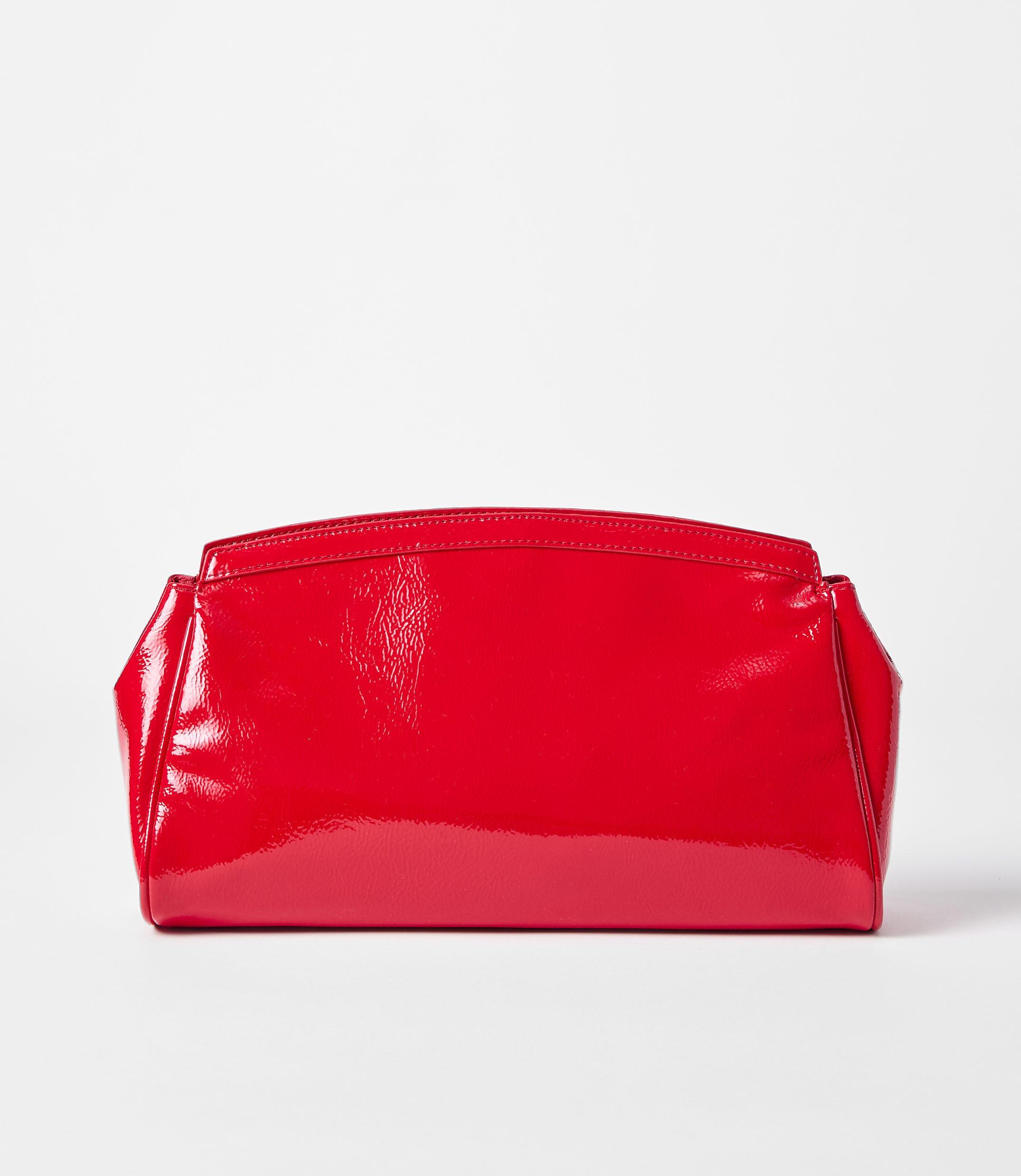 A shiny red clutch rests on a white surface against a plain white background.