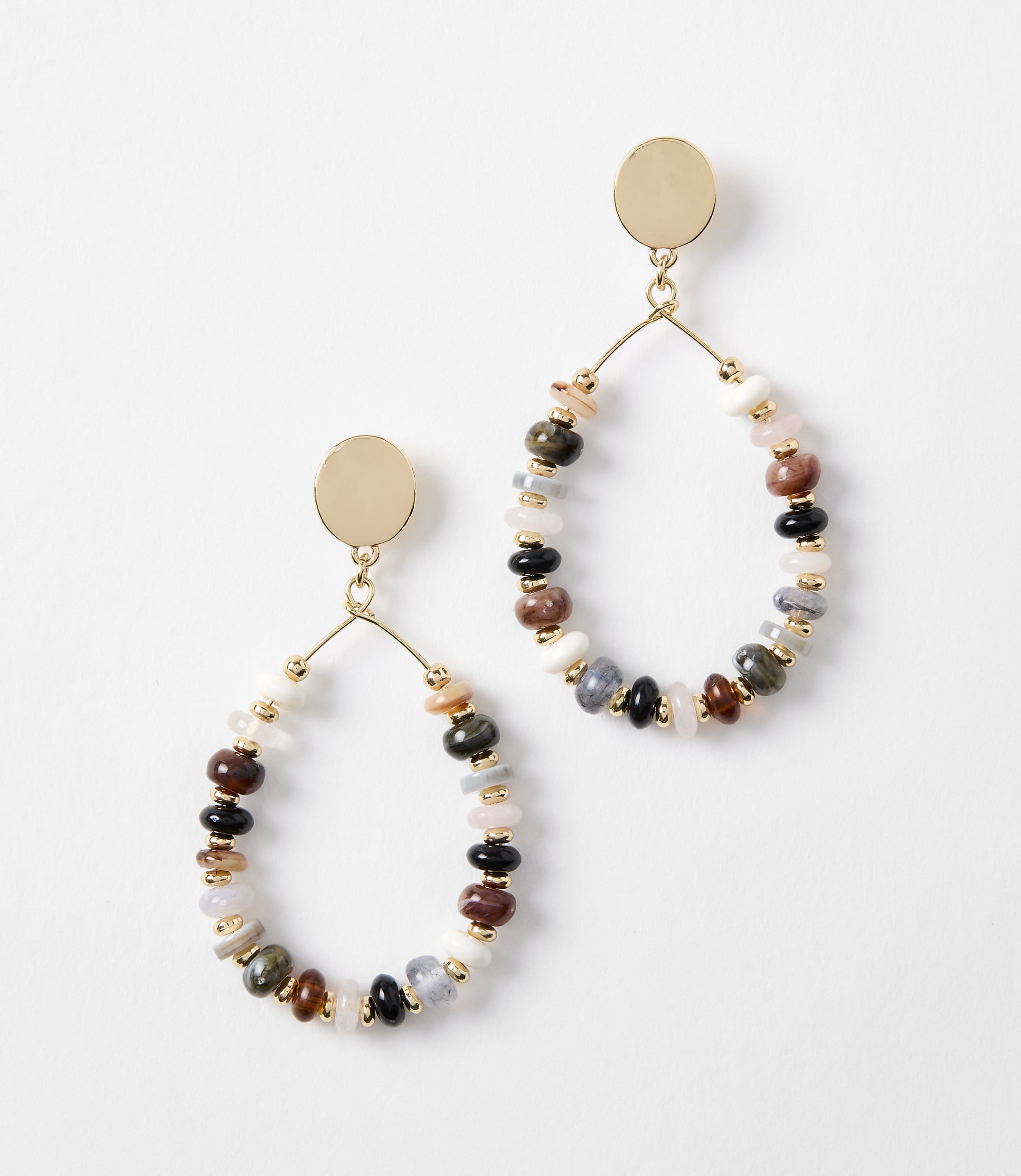 A pair of oval-shaped earrings with colorful beads and gold accents hang against a plain white background.