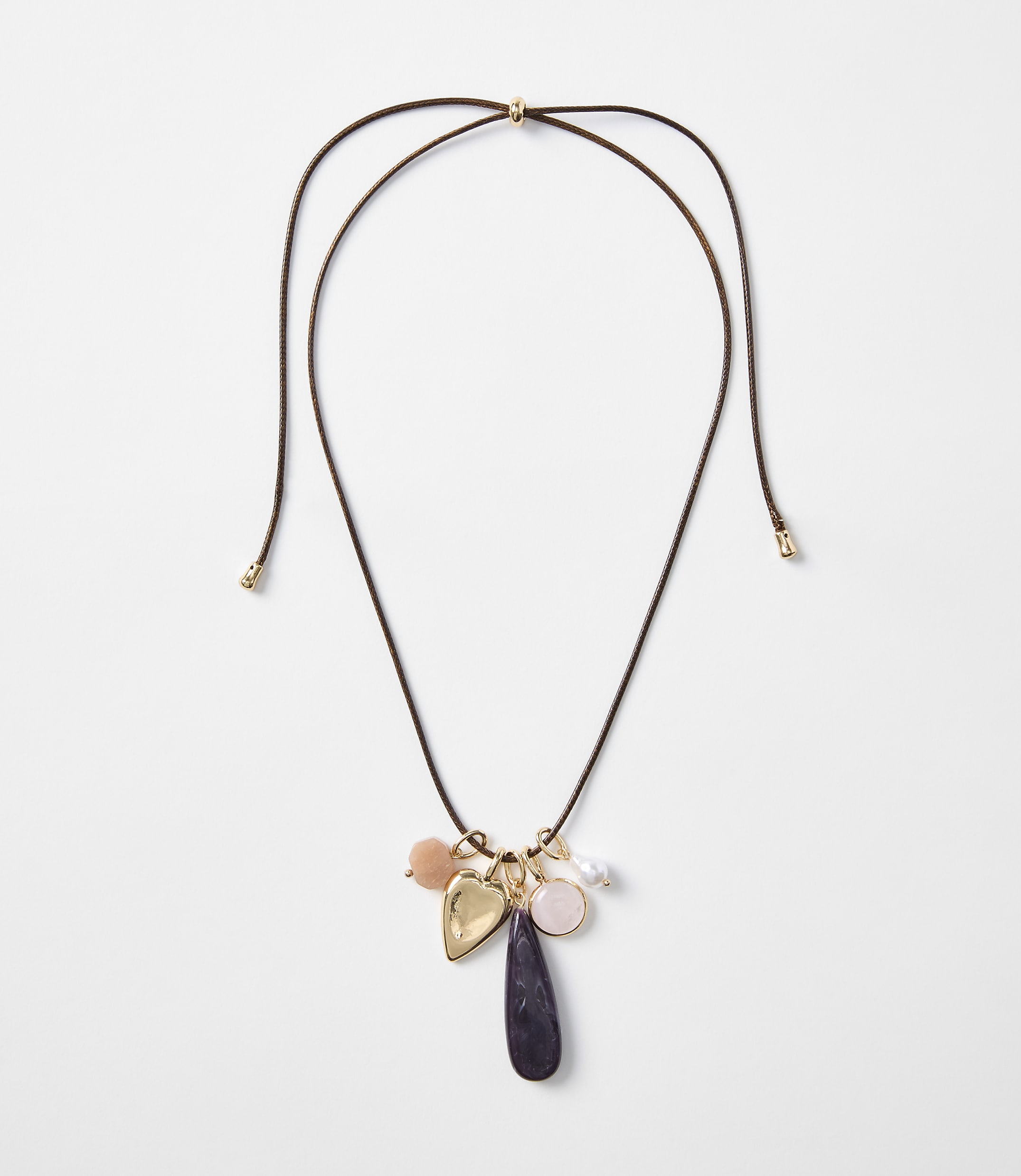 A delicate brown cord necklace with various charms, including a heart and a teardrop-shaped stone, hangs against a plain white background.